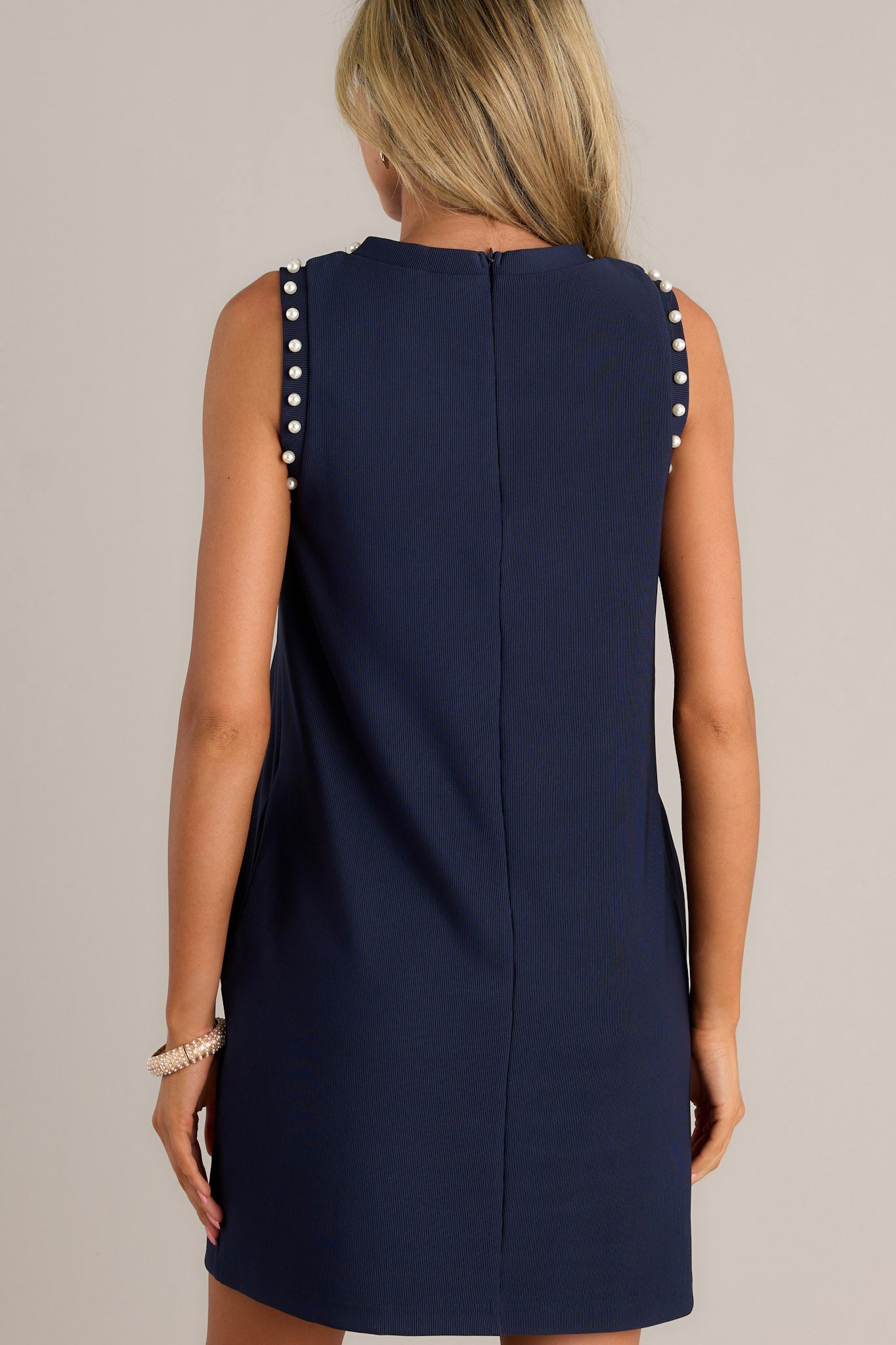 Back view of a navy mini dress highlighting the discrete zipper, ribbed texture, and overall fit.