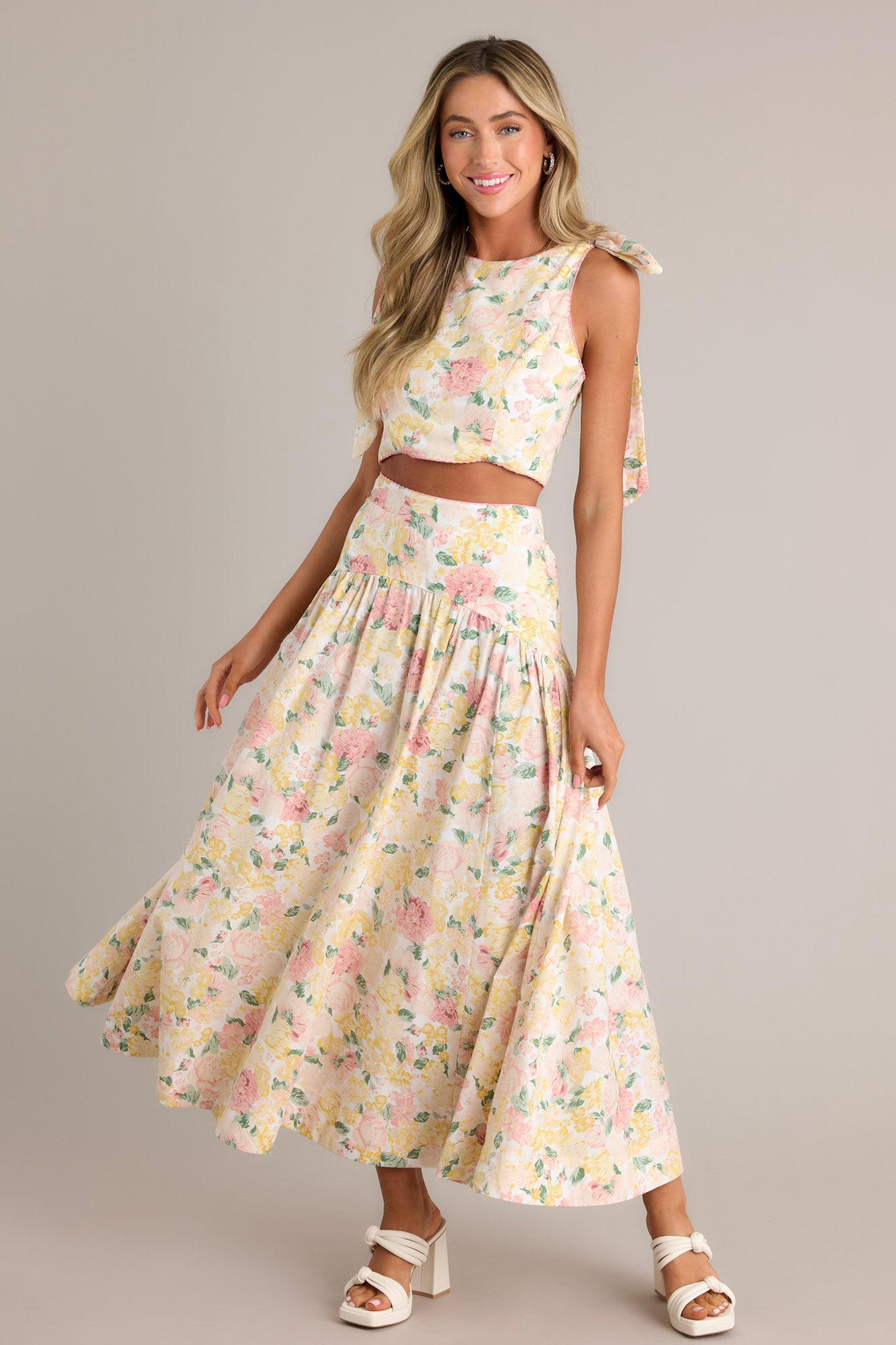 This ivory floral maxi skirt features a scalloped high waisted design, an elastic waist insert, a discrete side zipper, gathering around the hips, and a flowing silhouette.