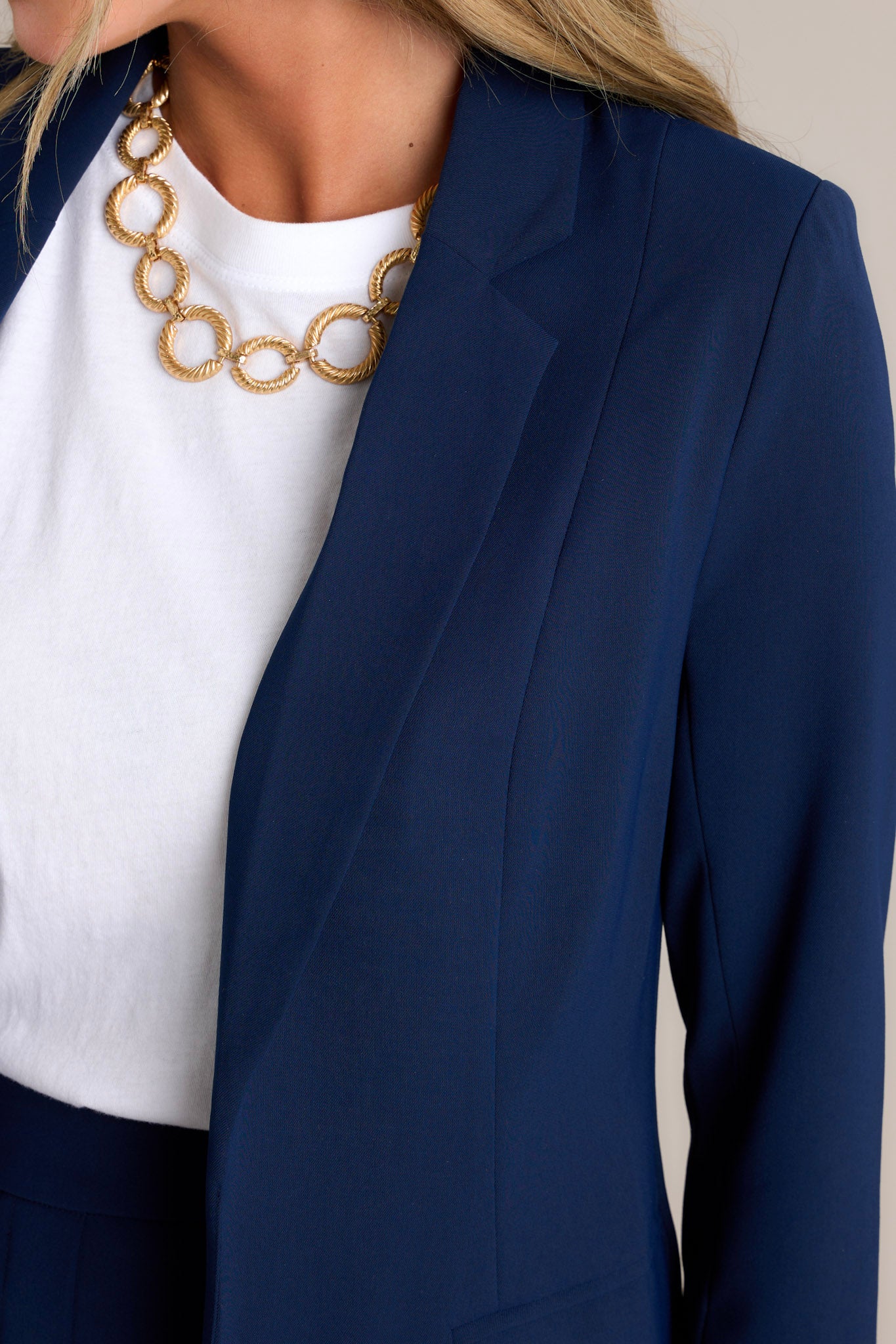 Close-up of the navy blazer showing the notched lapel collared neckline, floral lining, and functional pockets.