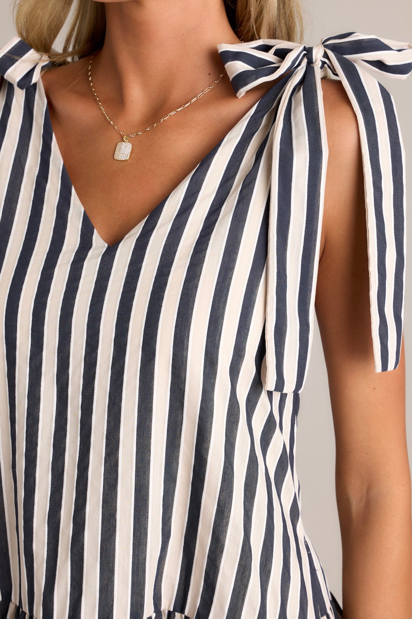 Close-up of the black stripe mini dress showing the v-neckline, self-tie straps, and functional hip pockets.