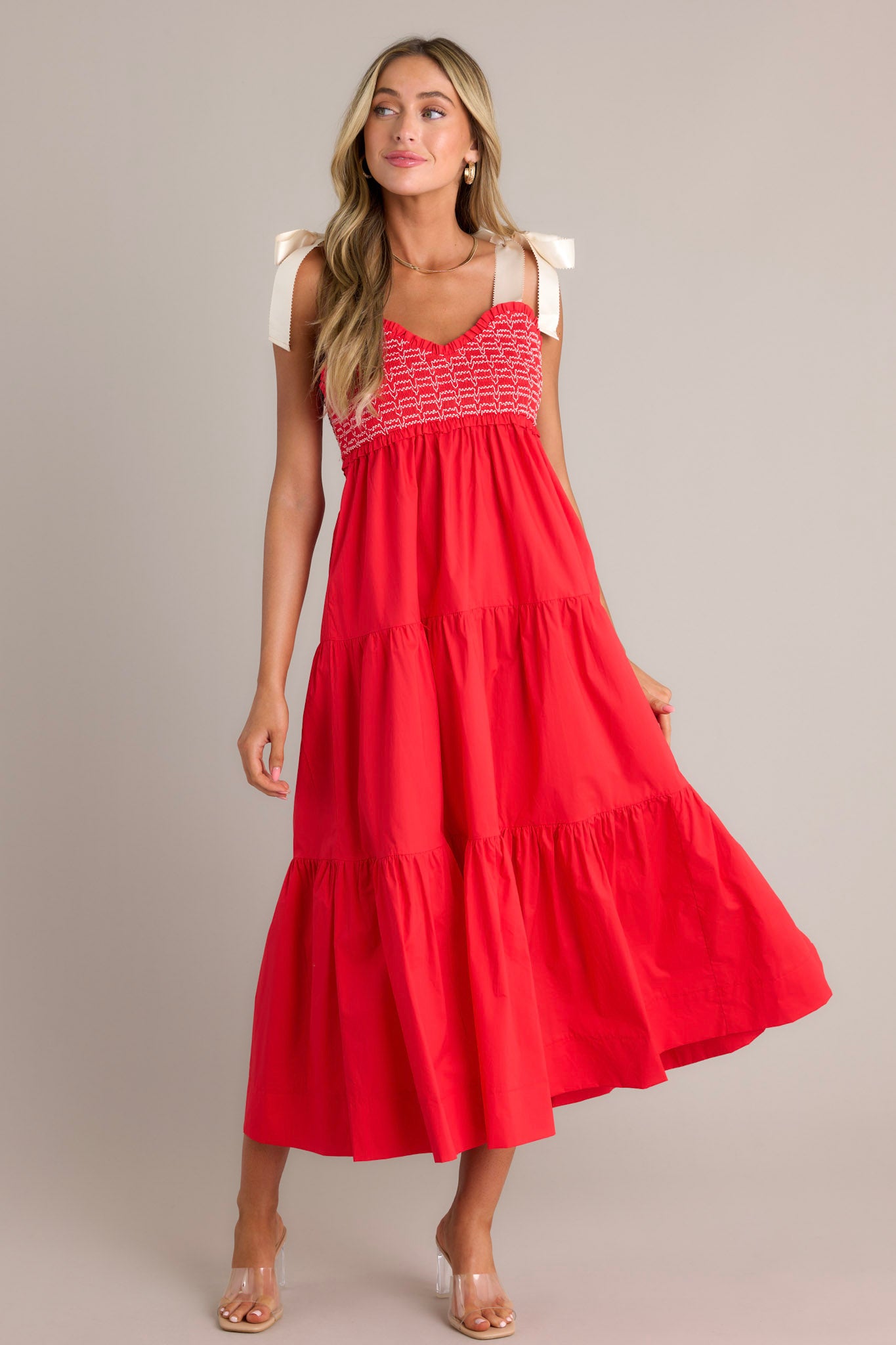 Full length view of a red maxi dress with a v-neckline, thick self-tie straps, a fully smocked bodice, functional hip pockets, and a tiered design