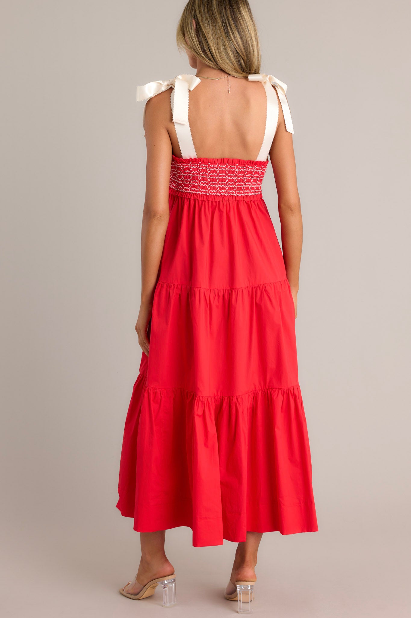 Back view of a red maxi dress highlighting the thick self-tie straps, fully smocked bodice, and overall fit.