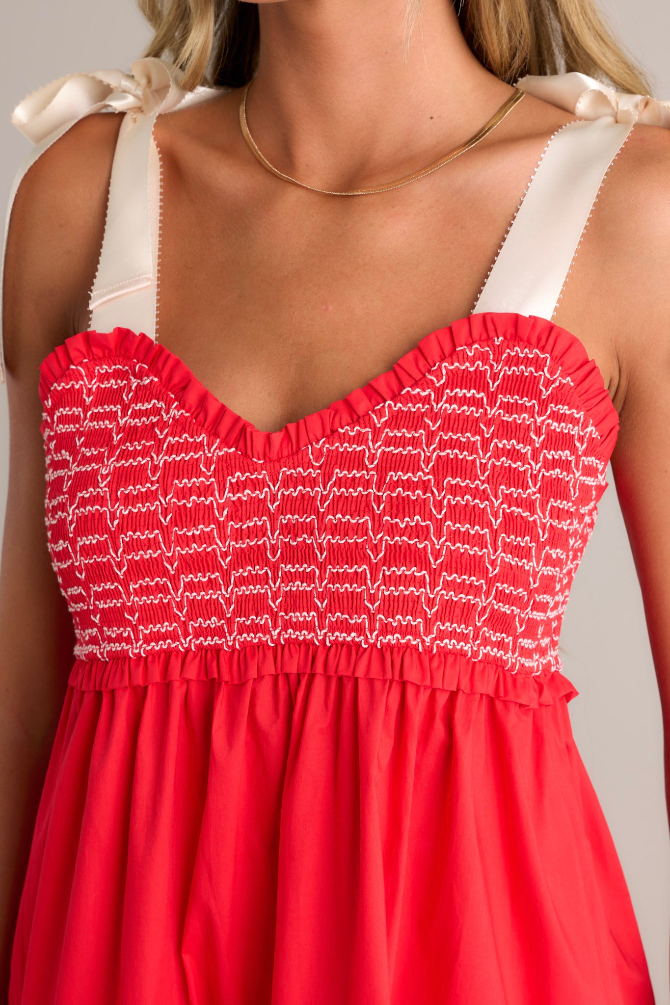 Close-up of the red maxi dress showing the v-neckline, fully smocked bodice, and tiered design.