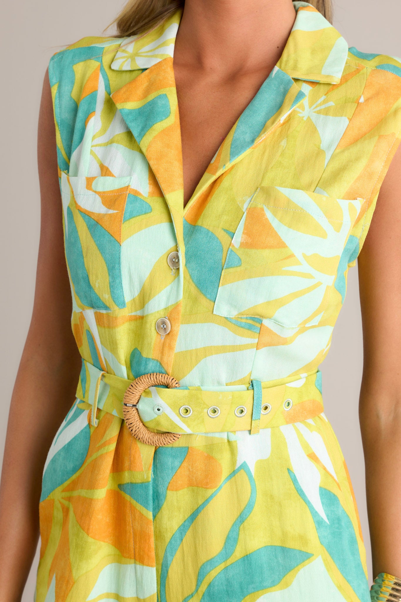 Close-up of the lime green jumpsuit showing the notched lapel collared v-neckline, functional buttons, and breast pockets.