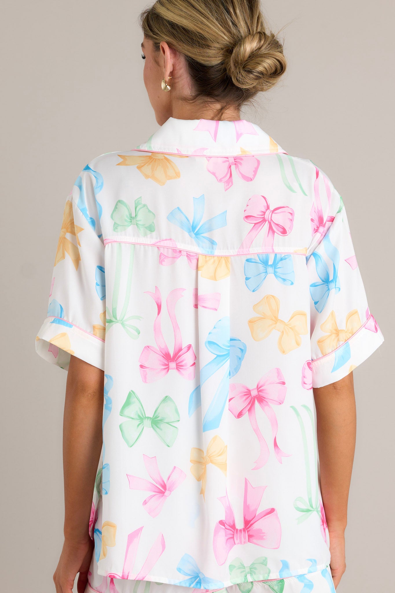 Back view of a white pajama top highlighting the overall fit, multi-color bow print, and split hemline.