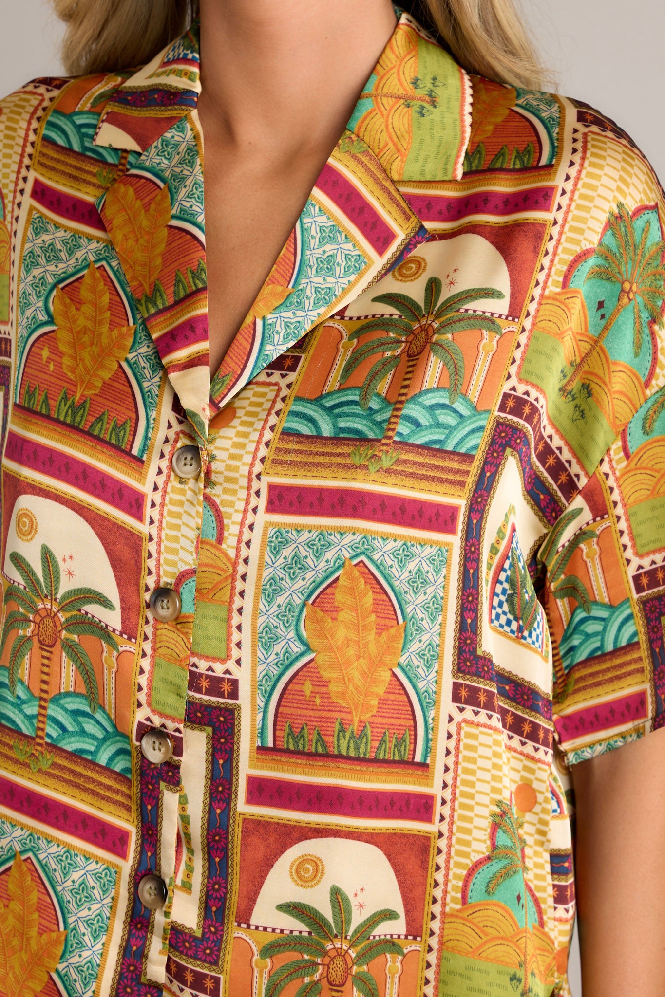 Close-up of the mustard top showing the notched lapel collared neckline, functional buttons, and unique print.