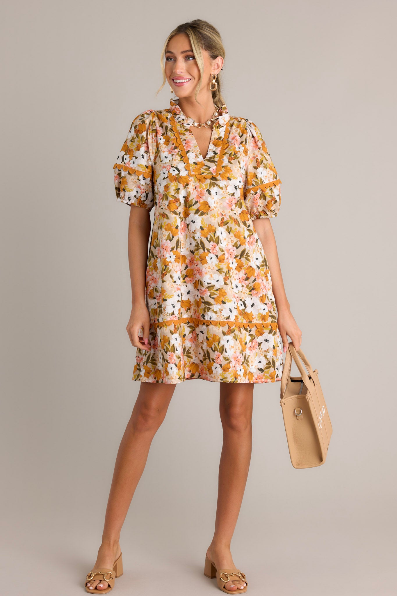 This yellow mini dress features a ruffled v-neckline, scalloped detailing, a relaxed fit, and elastic cuffed short sleeves.