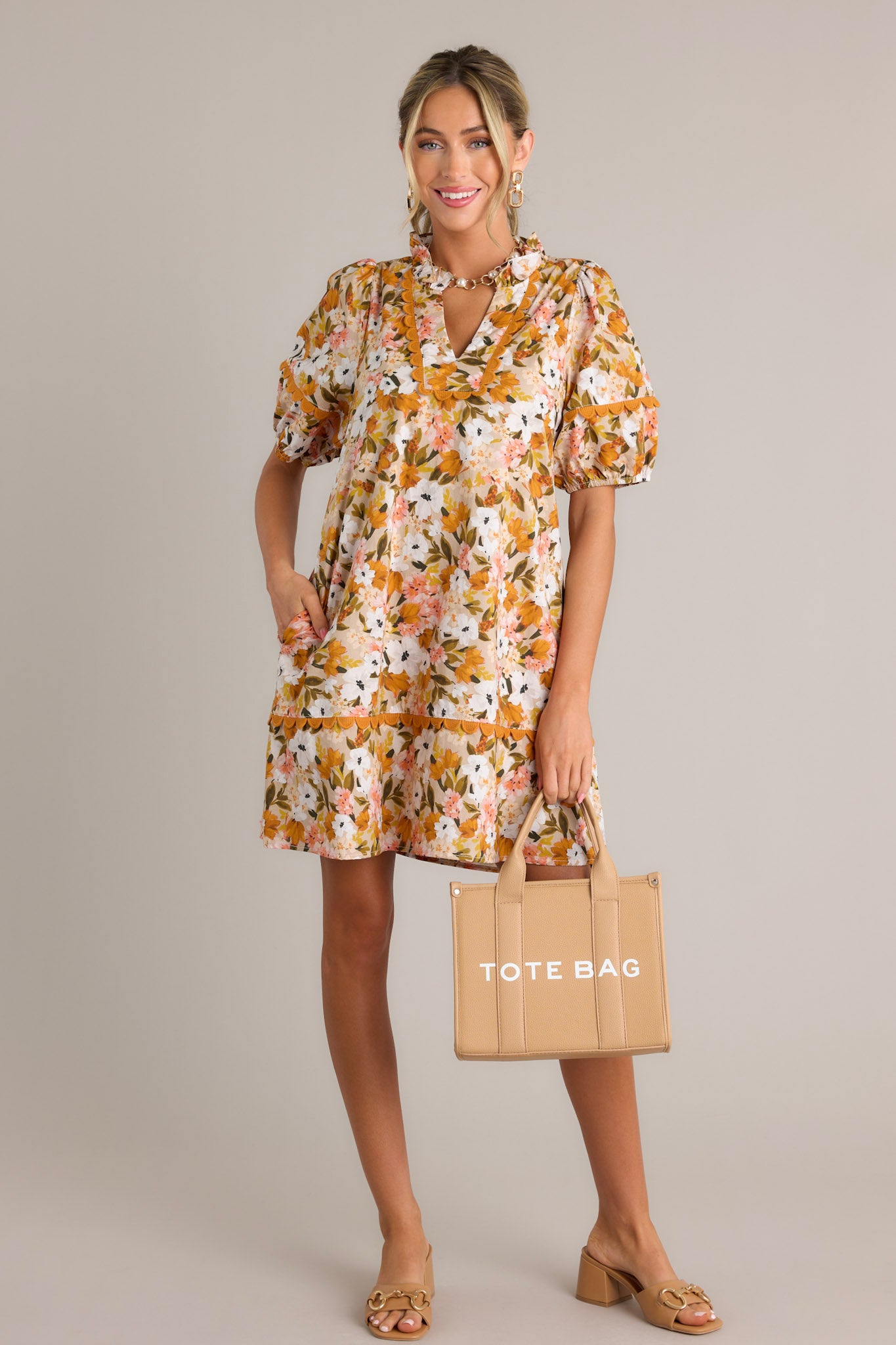 Full length view of a yellow mini dress with a ruffled v-neckline, scalloped detailing, a relaxed fit, and elastic cuffed short sleeves