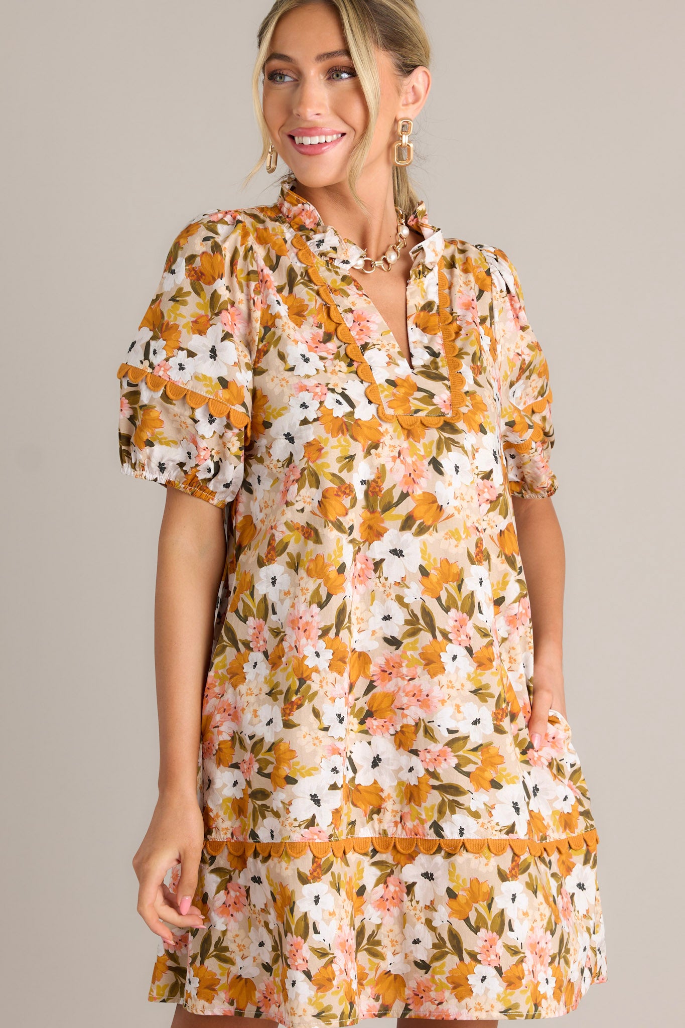 Front view of a yellow mini dress featuring a ruffled v-neckline, scalloped detailing, a relaxed fit, and elastic cuffed short sleeves.