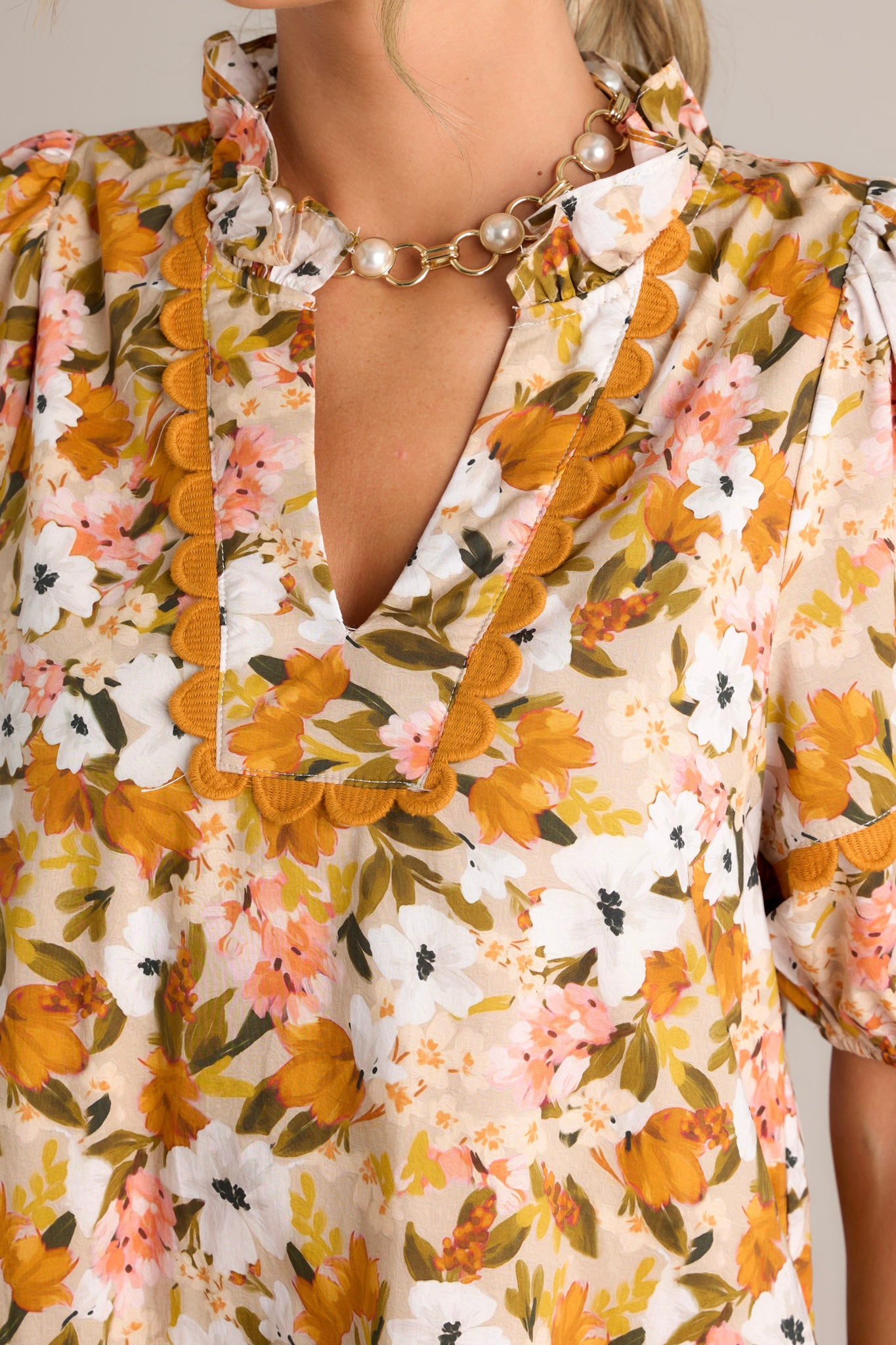 Close-up of the yellow mini dress showing the ruffled v-neckline, scalloped detailing, and elastic cuffed short sleeves.