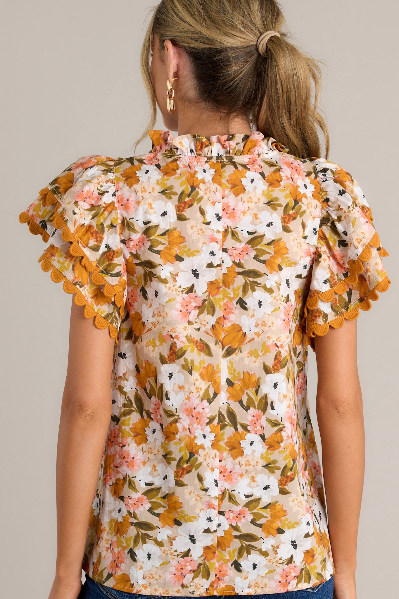 Back view of a yellow top highlighting the overall fit, lightweight material, and layered scalloped short sleeves.