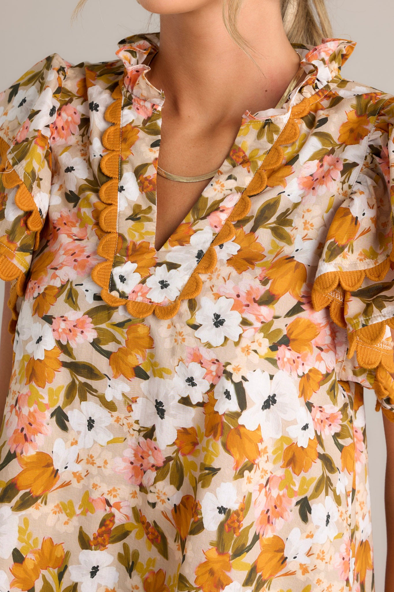 Close-up of the yellow top showing the ruffled v-neckline, scalloped detailing, and lightweight material.