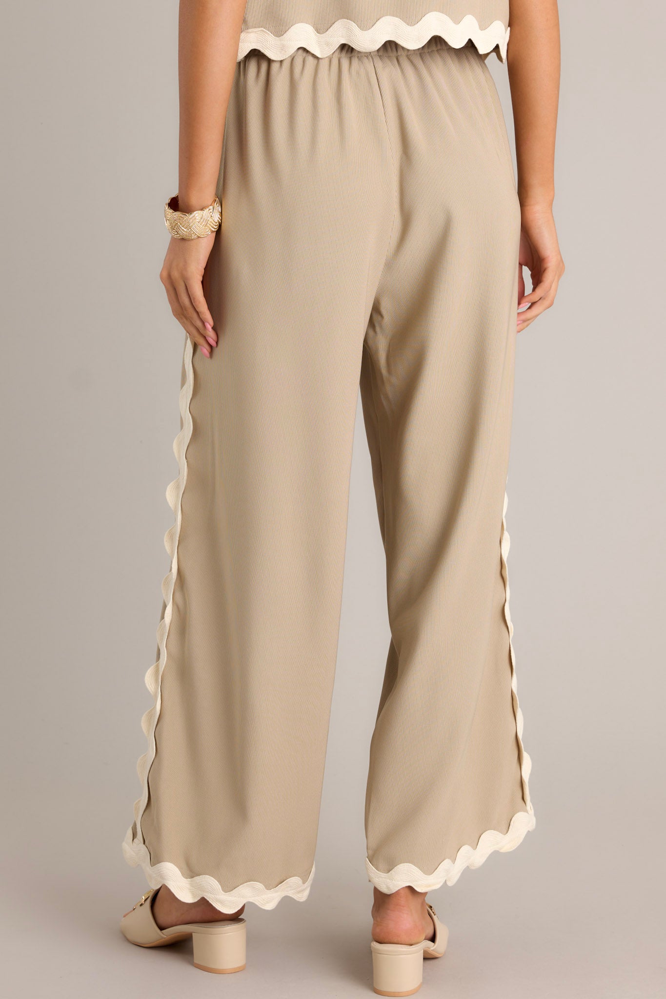 Back view of taupe pants highlighting the ribbed texture, ricrac hemlines, and overall fit.