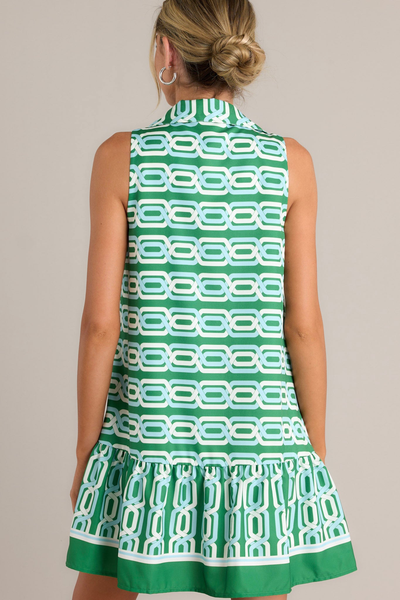 Back view of a green multi mini dress highlighting the unique pattern, single tier, and overall fit.