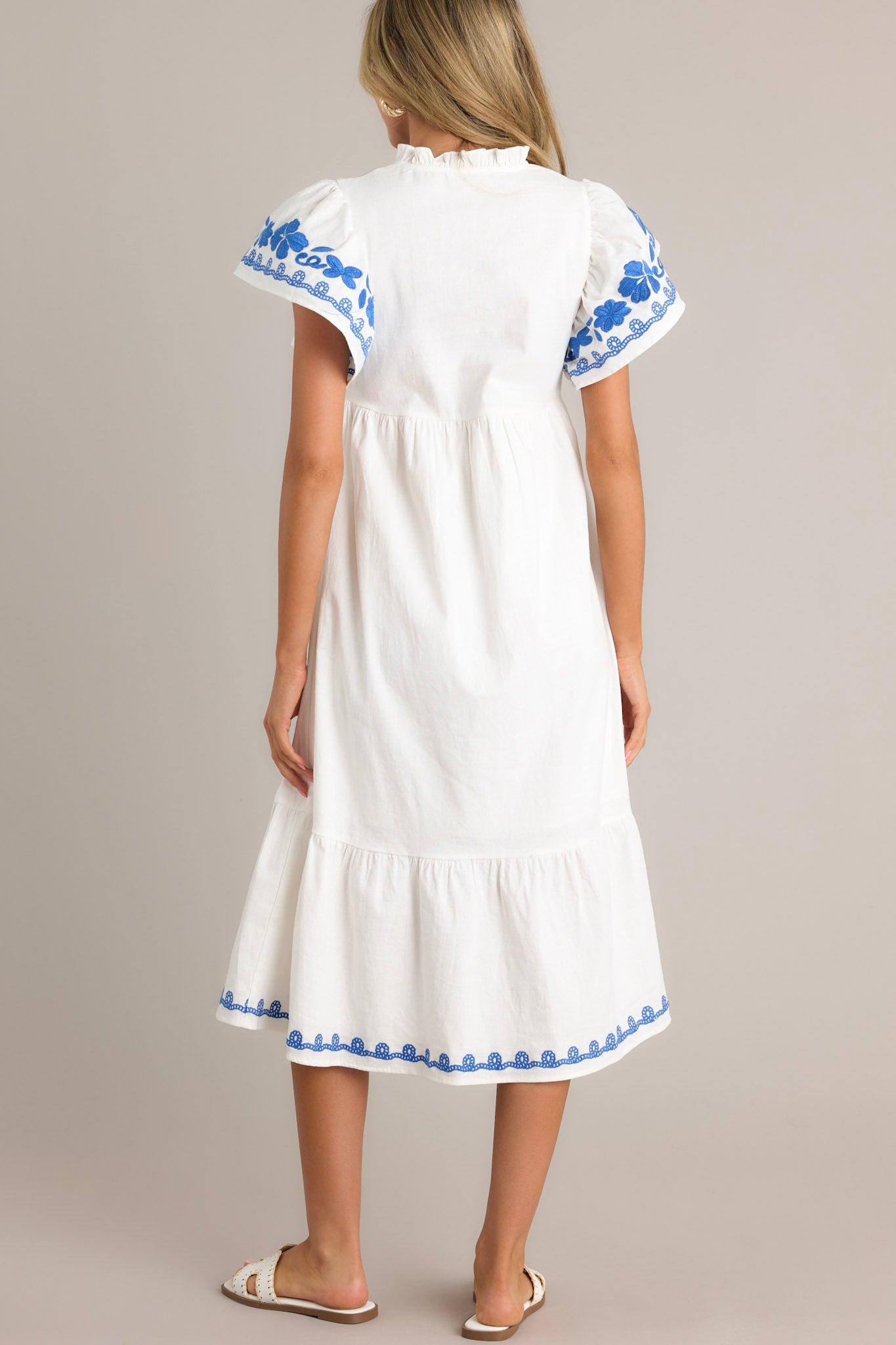 Back view of an ivory midi dress highlighting the overall fit and the embroidered hemline.