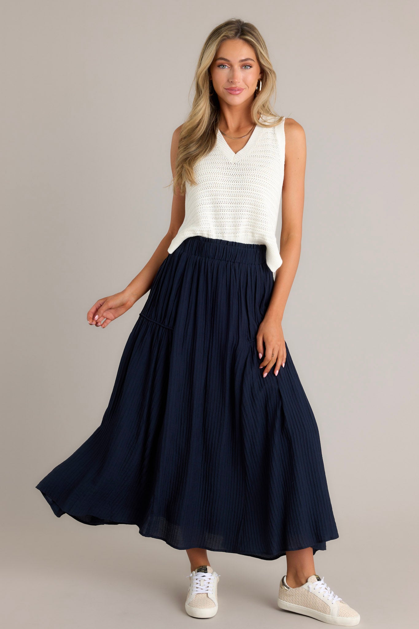 Full length view of a navy skirt with a high waist design, an elastic waistband, a ribbed texture, and a flowing silhouette