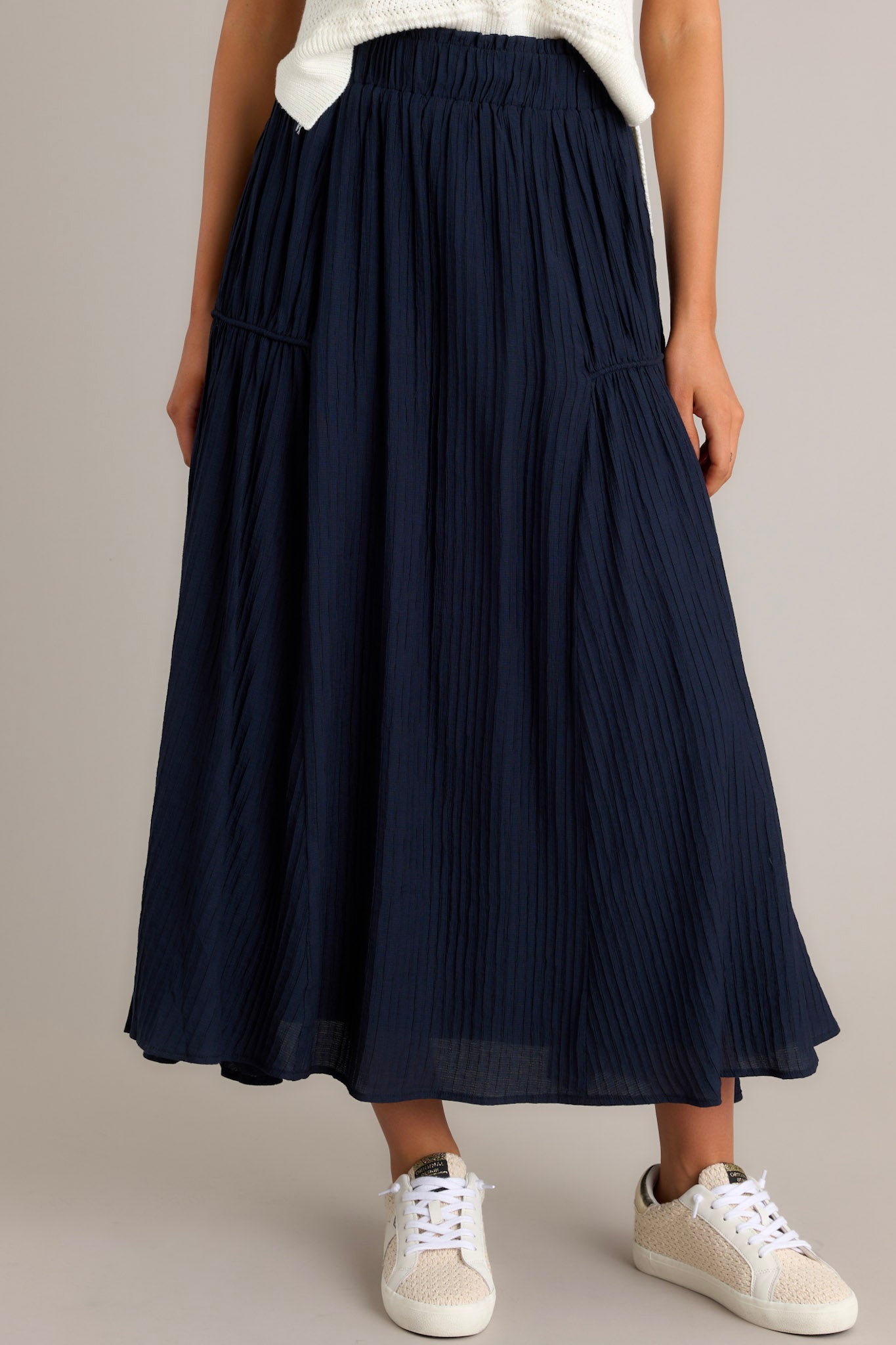 Front view of a navy skirt featuring a high waist design, an elastic waistband, a ribbed texture, and a flowing silhouette.