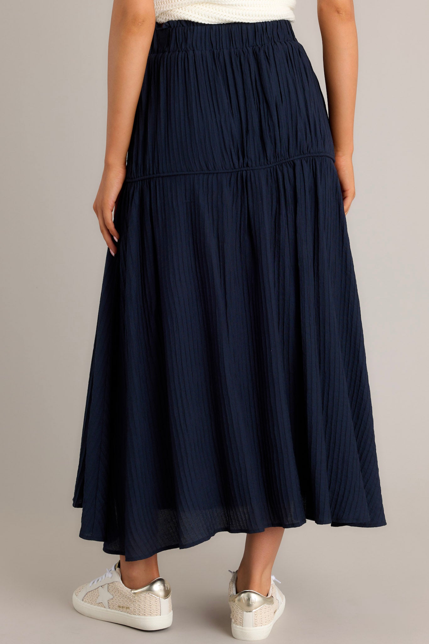 Back view of a navy skirt highlighting the high waist design, elastic waistband, and the ribbed texture.