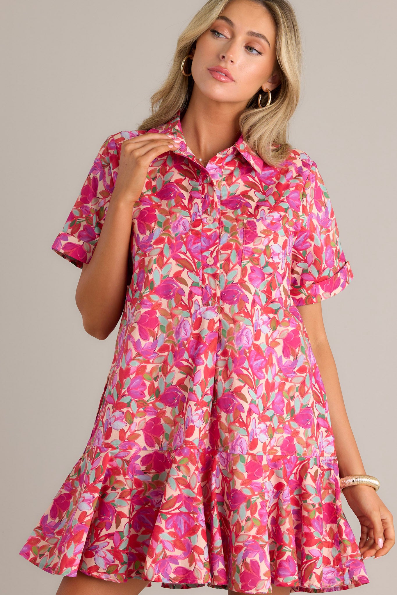 Front view of a pink mini dress featuring a collared neckline, a breast pocket, a button front bodice, functional hip pockets, a single tier, and cuffed short sleeves.