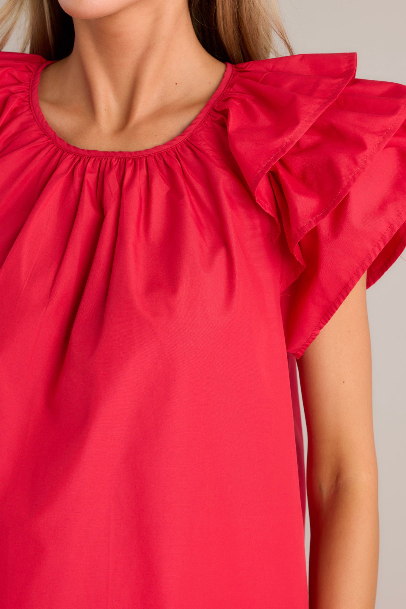 Close-up of the red top showing the rounded neckline, gathering at the neckline, and the keyhole with a button closure.