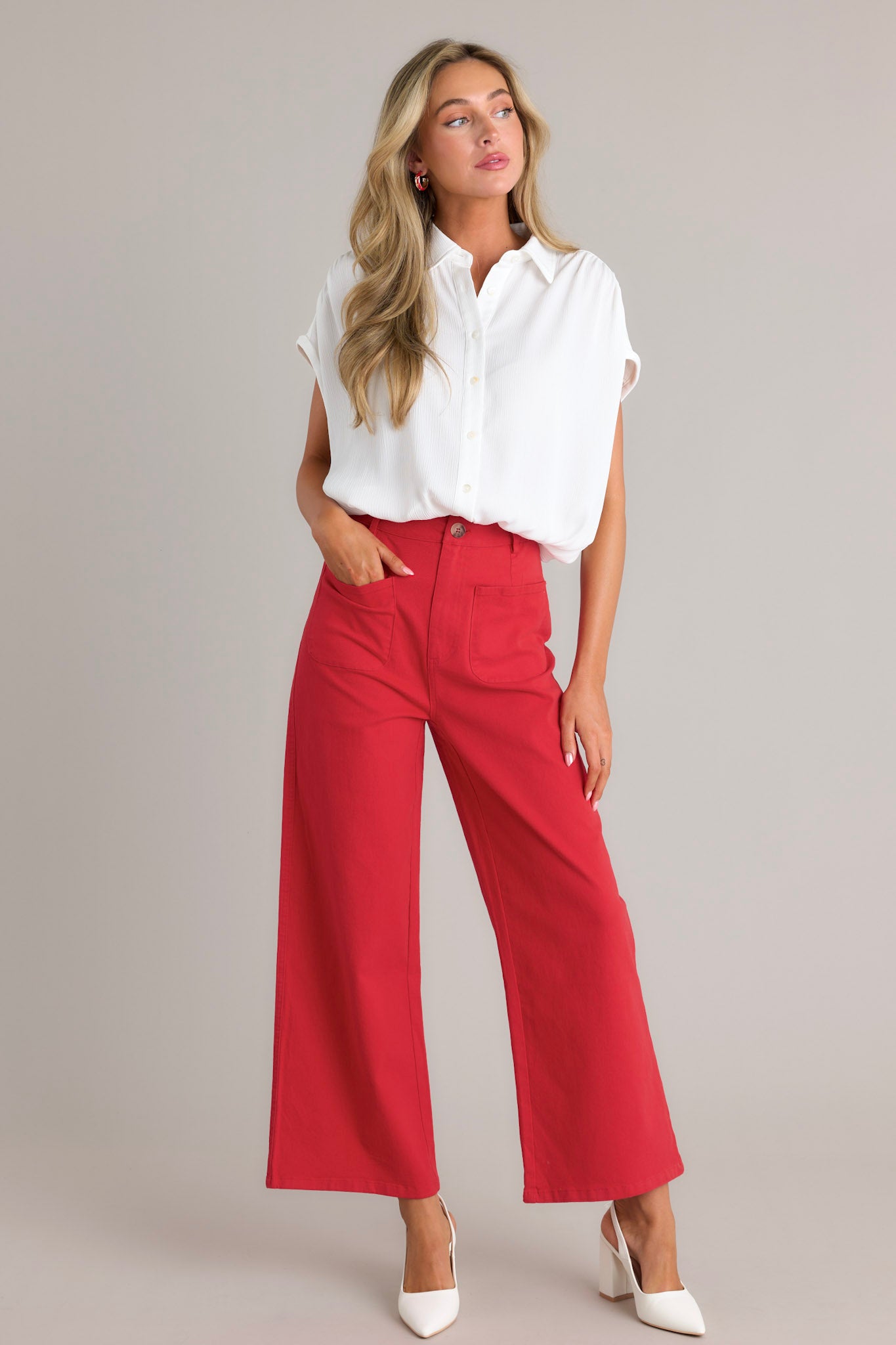 These red pants feature a high waisted design, classic button &amp; zipper closure, belt loops, functional front pockets, faux back pockets, and a wide leg design.