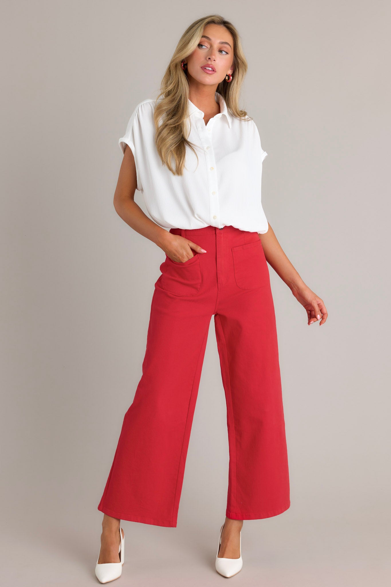 Front angled view of red pants featuring a high waisted design, classic button & zipper closure, belt loops, functional front pockets, faux back pockets, and a wide leg design.