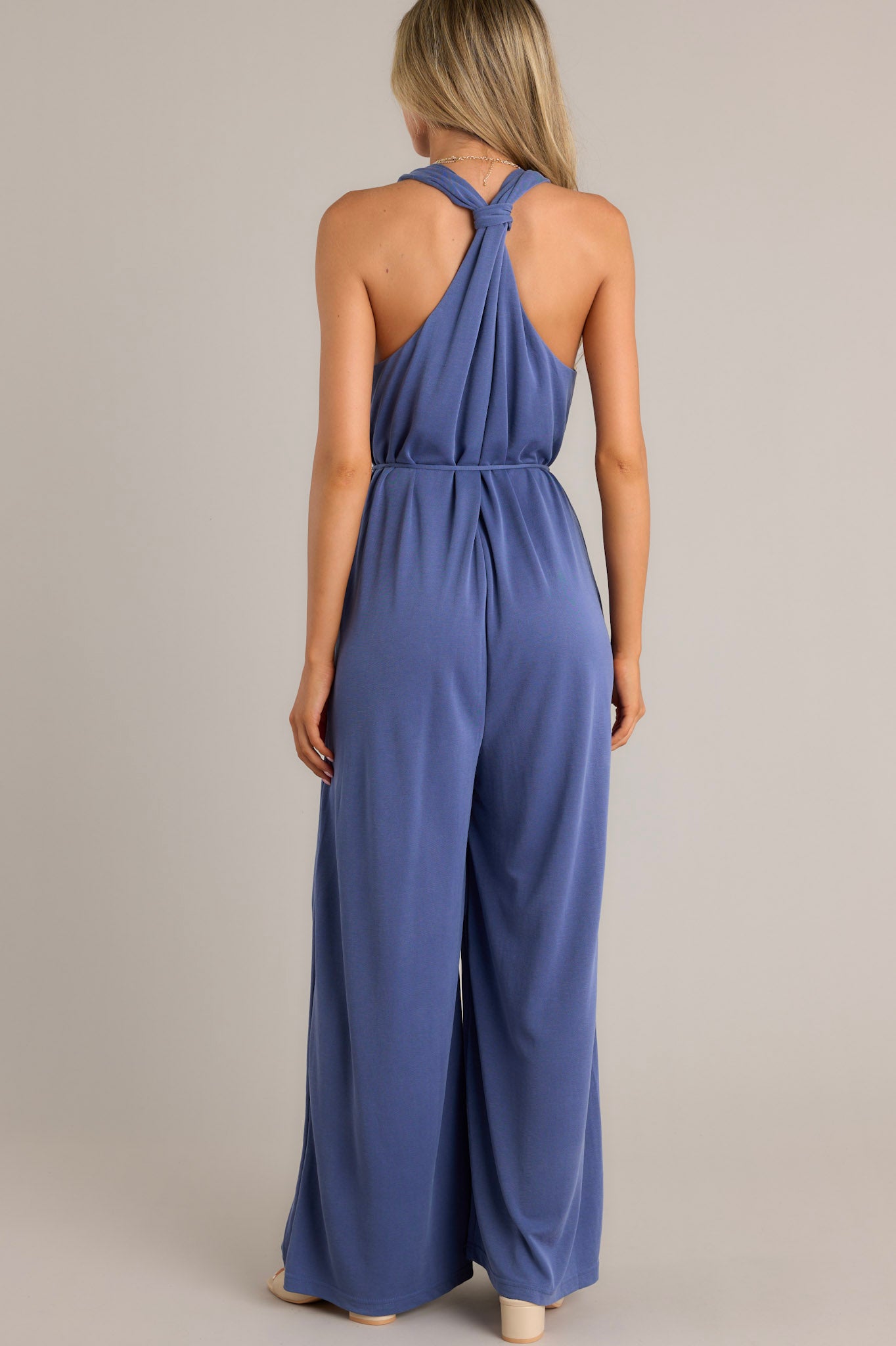 Back view of a violet blue jumpsuit highlighting the racerback and wide leg design.