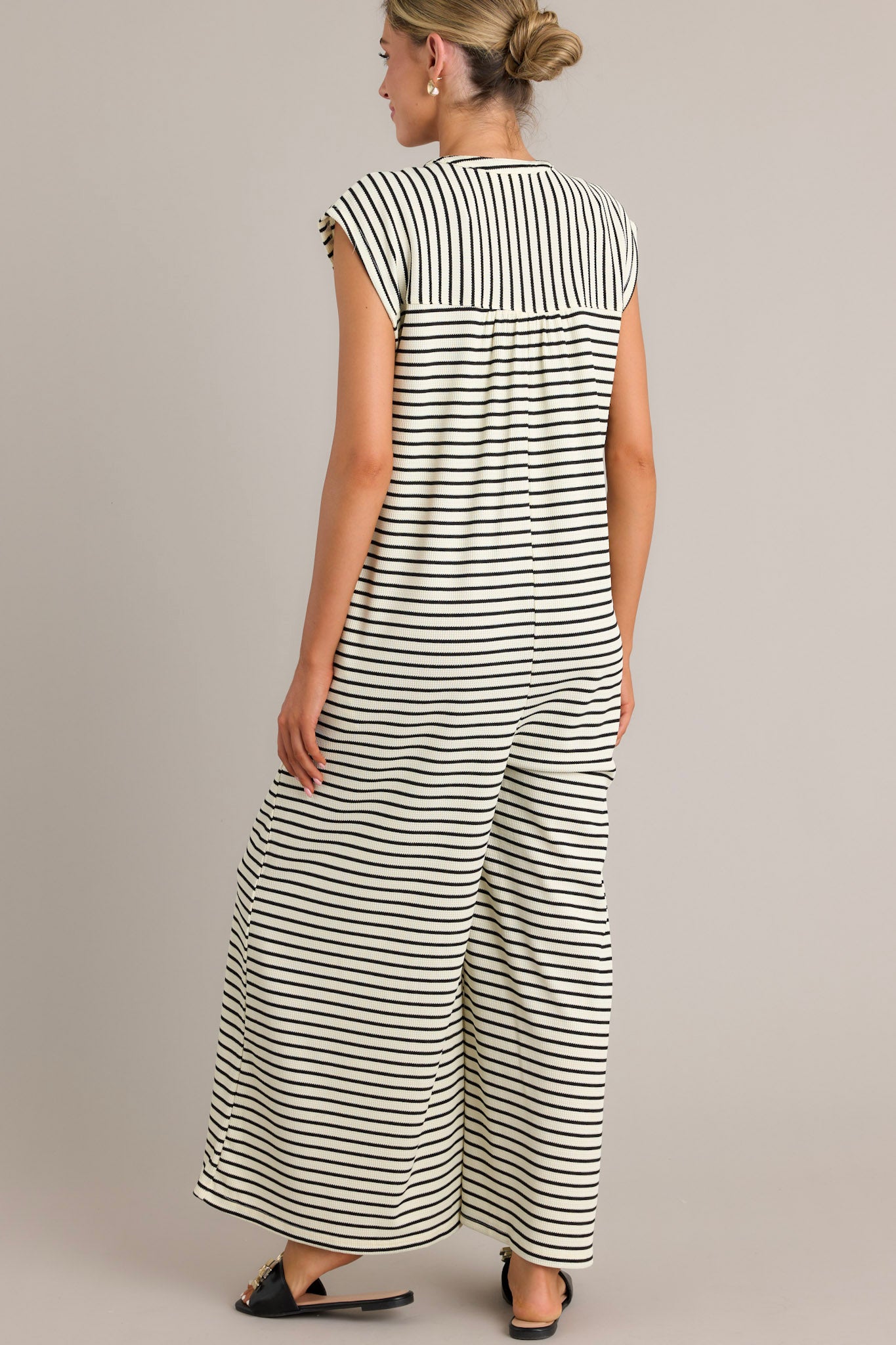 Back view of a black striped jumpsuit highlighting the textured material and sleeveless design.