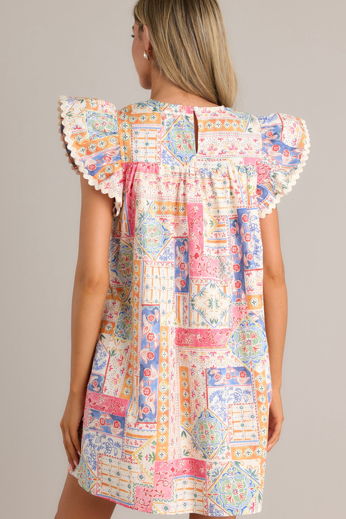 Back view of a patchwork mini dress highlighting the unique patchwork design and ricrac trim flutter sleeves.