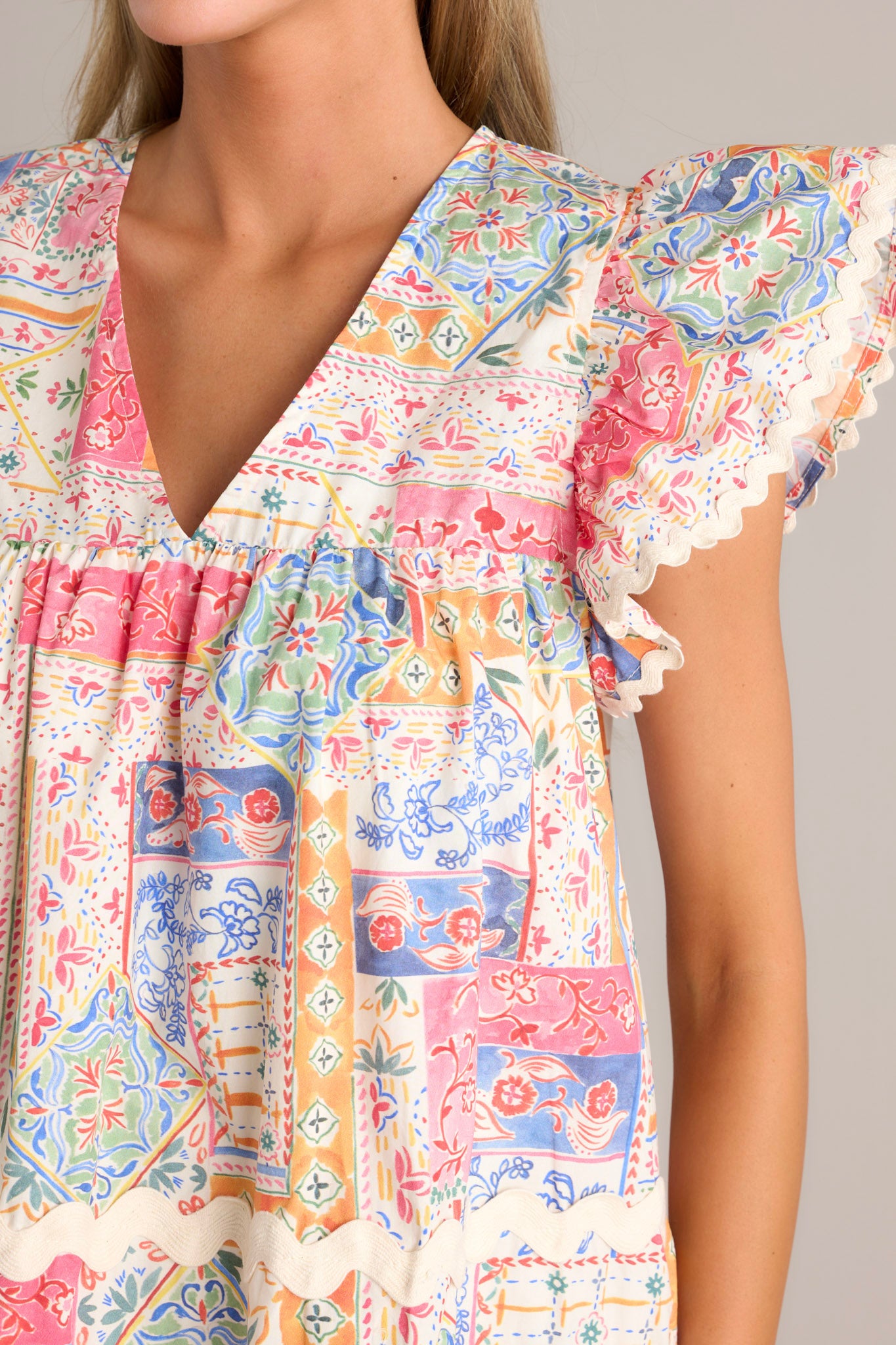 Close-up of the patchwork mini dress showing the v-neckline, ricrac detailing, and ricrac trim flutter sleeves.