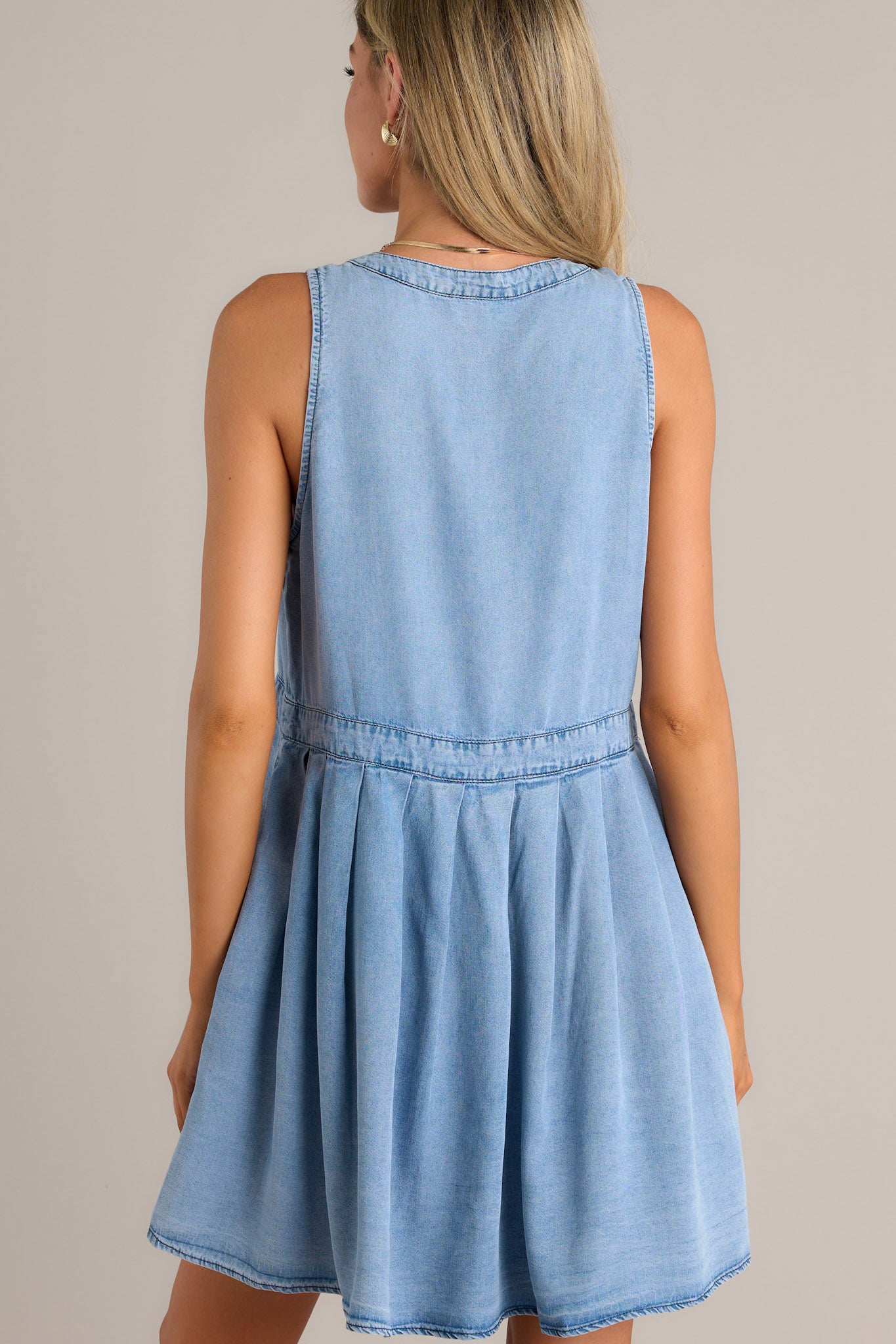 Back view of a chambray mini dress highlighting the thick waistband and overall fit.