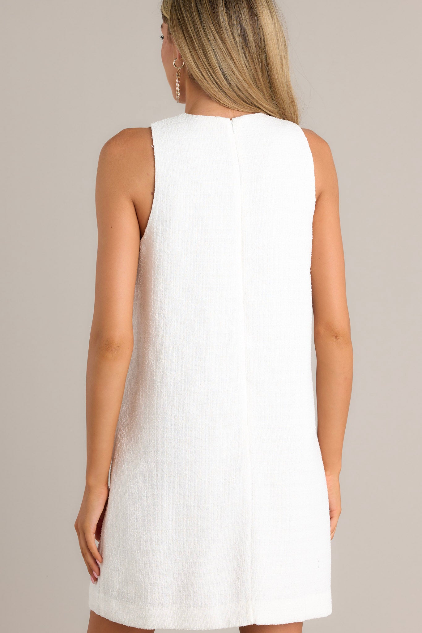 Back view of a white mini dress highlighting the discrete zipper down the back and the straight silhouette.