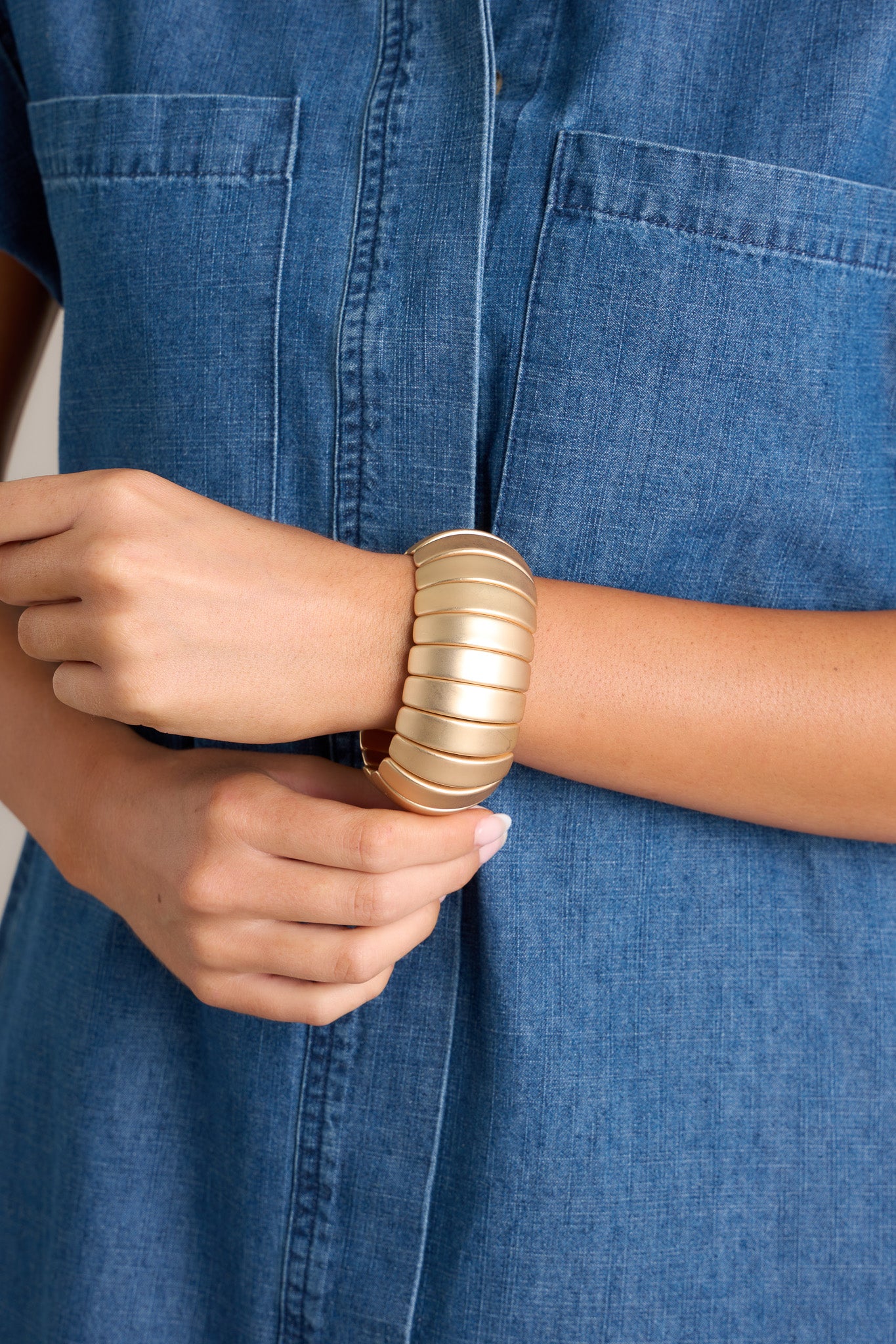 This bracelet features gold hardware, curved horizontal beading, and an elastic band underneath.