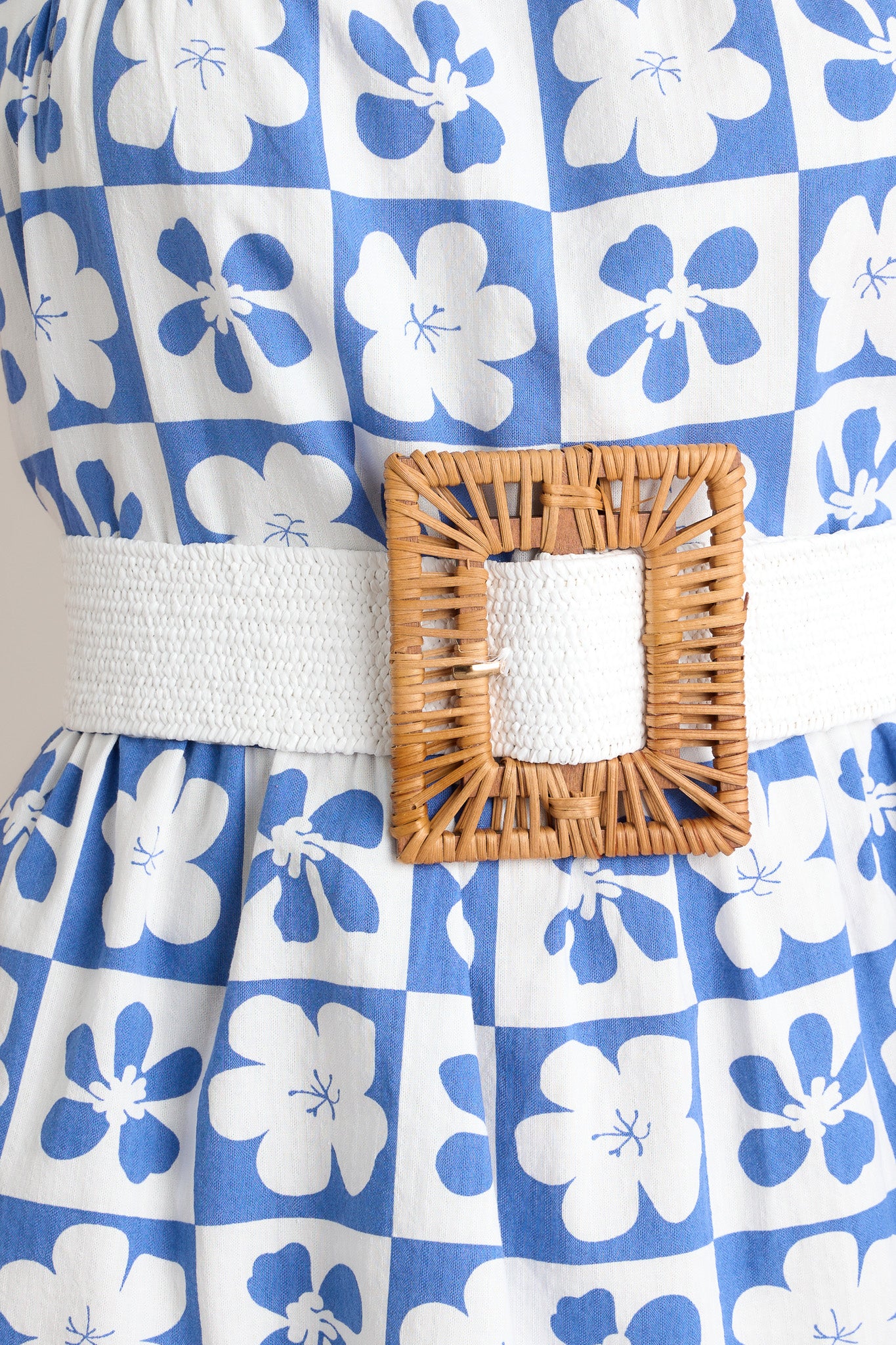 Close up view of this white belt featuring a stretchy band and a natural square buckle. 