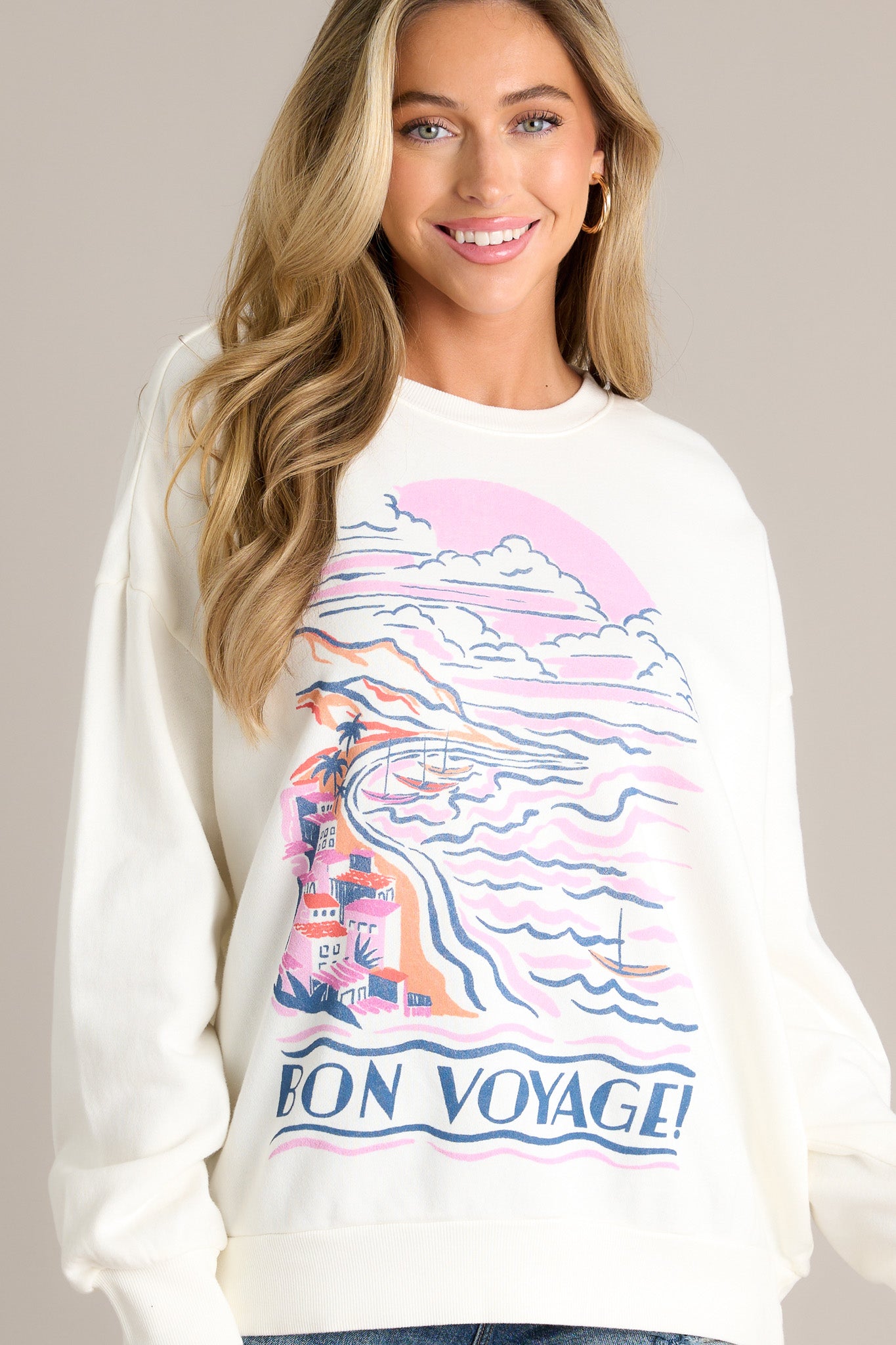 Front angled view of an ivory sweatshirt featuring a ribbed crew neckline, a large print, a thick ribbed hemline, and ribbed cuffed long sleeves