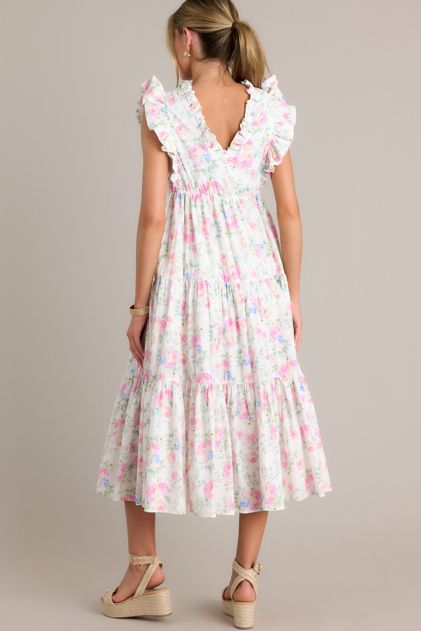 Back view of an ivory floral midi dress highlighting the overall fit, tiers, and sleeveless design.