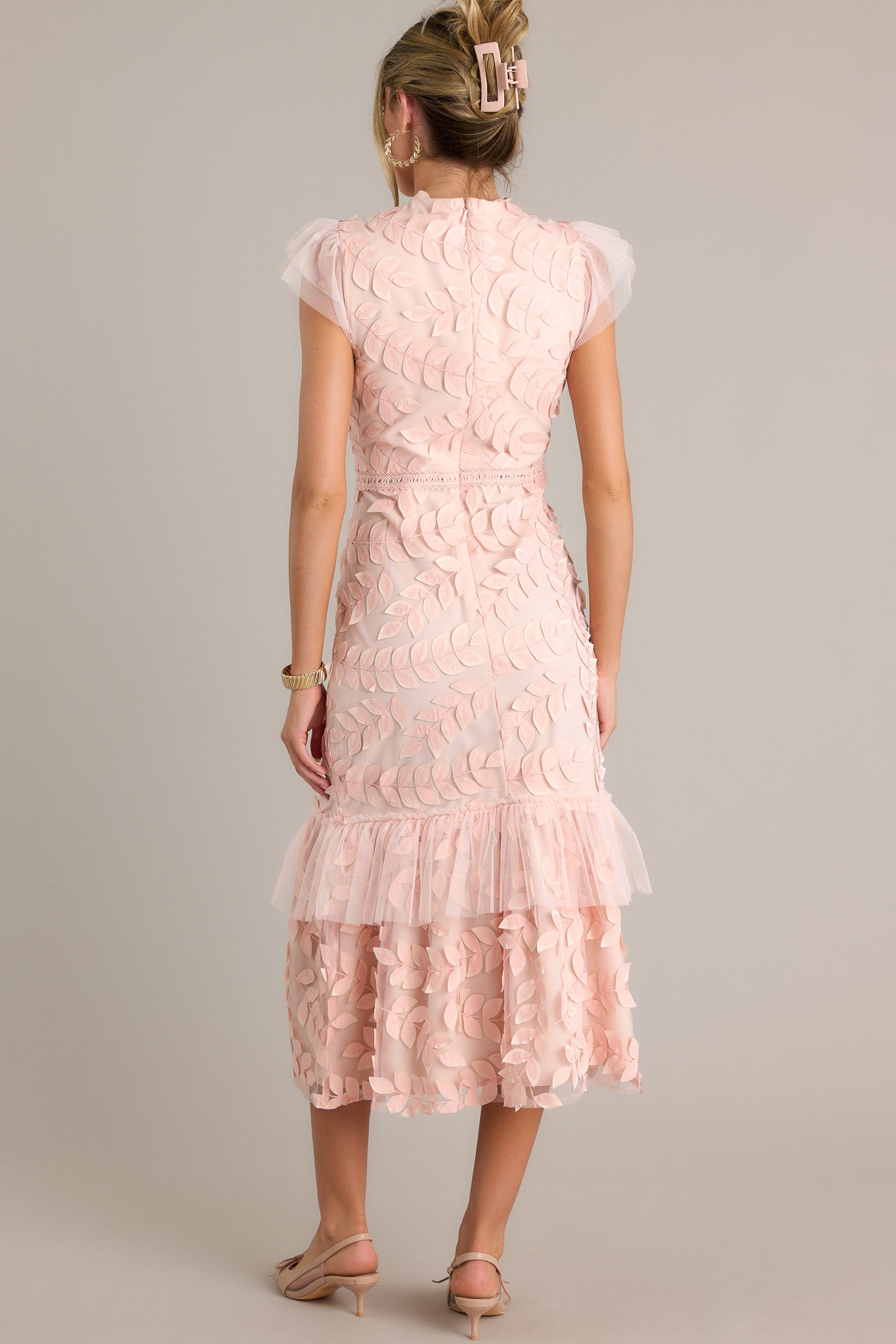 Back view of a light pink midi dress highlighting the discrete back zipper, lace tier, and overall fit.