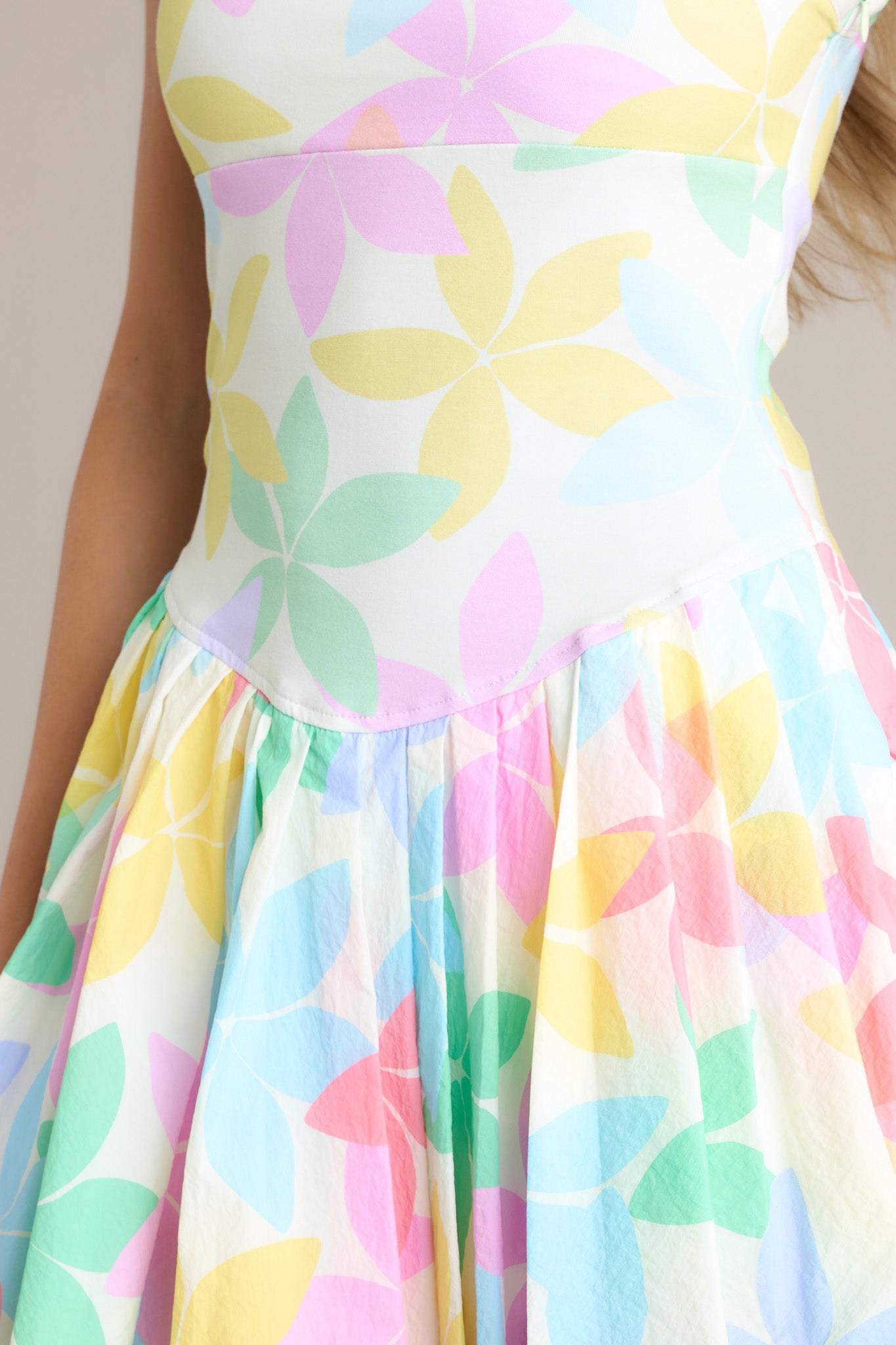 Close-up of the pastel mini dress focusing on the square neckline, thin straps, and the intricate pastel floral pattern on the pleated skirt