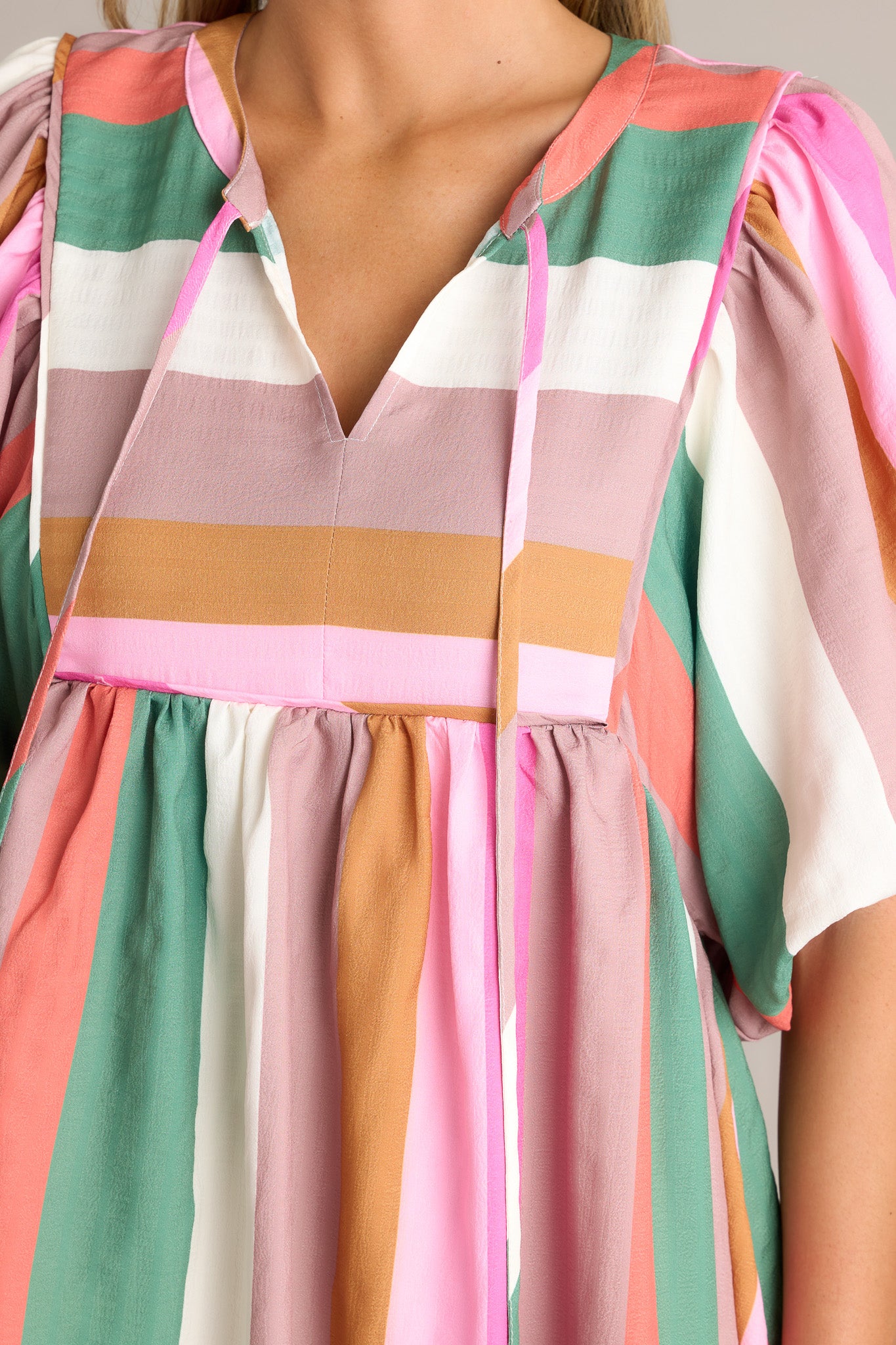 Close-up of the stripe dress showing the v-neckline, self-tie drawstring, and multi-colored stripes.