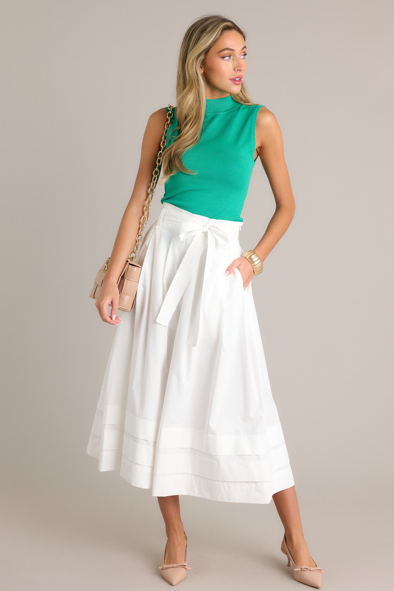 Full length view of a kelly green tank with a high ribbed neckline, 4 gold functional shoulder buttons, a fitted design, and a lightweight material