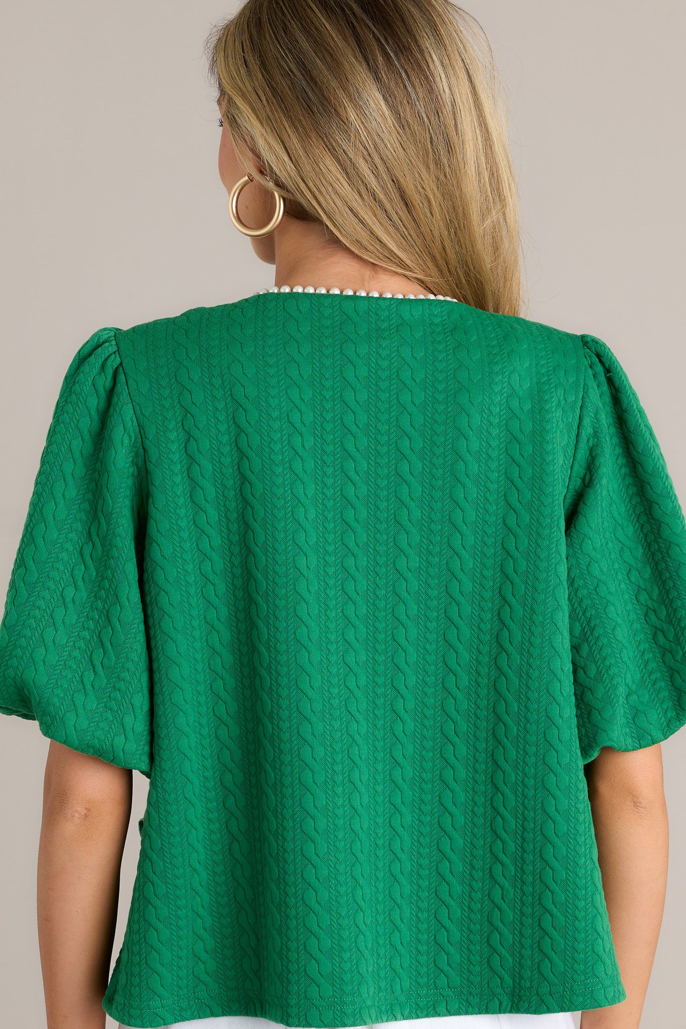 Back view of a green short sleeve jacket highlighting the overall fit, quilted design, and elastic cuffed puff sleeves.