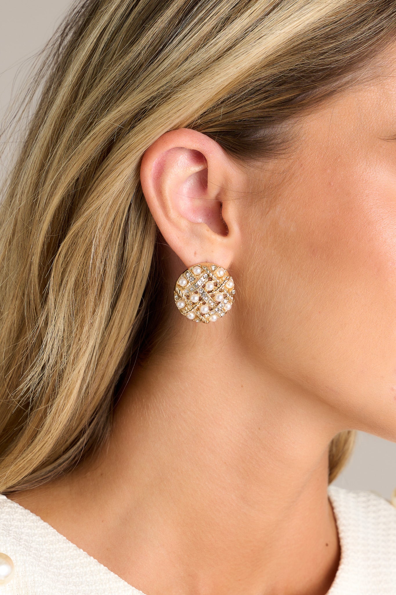 These gold cluster earrings feature a circular shape, an intricate lattice-like design, small faux pearls & rhinestones, and secure post backings.