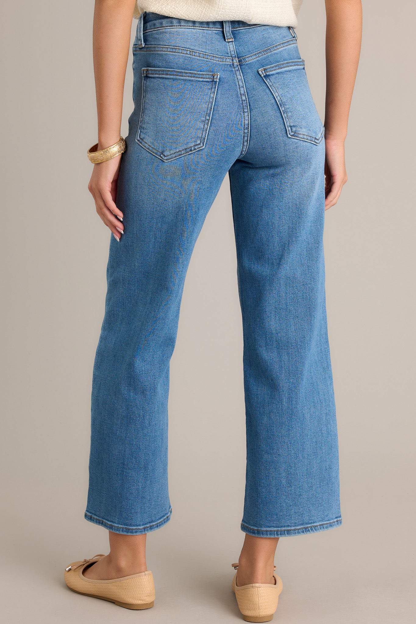 Back view of jeans highlighting the high waisted design, belt loops, functional back pockets, and cropped length.