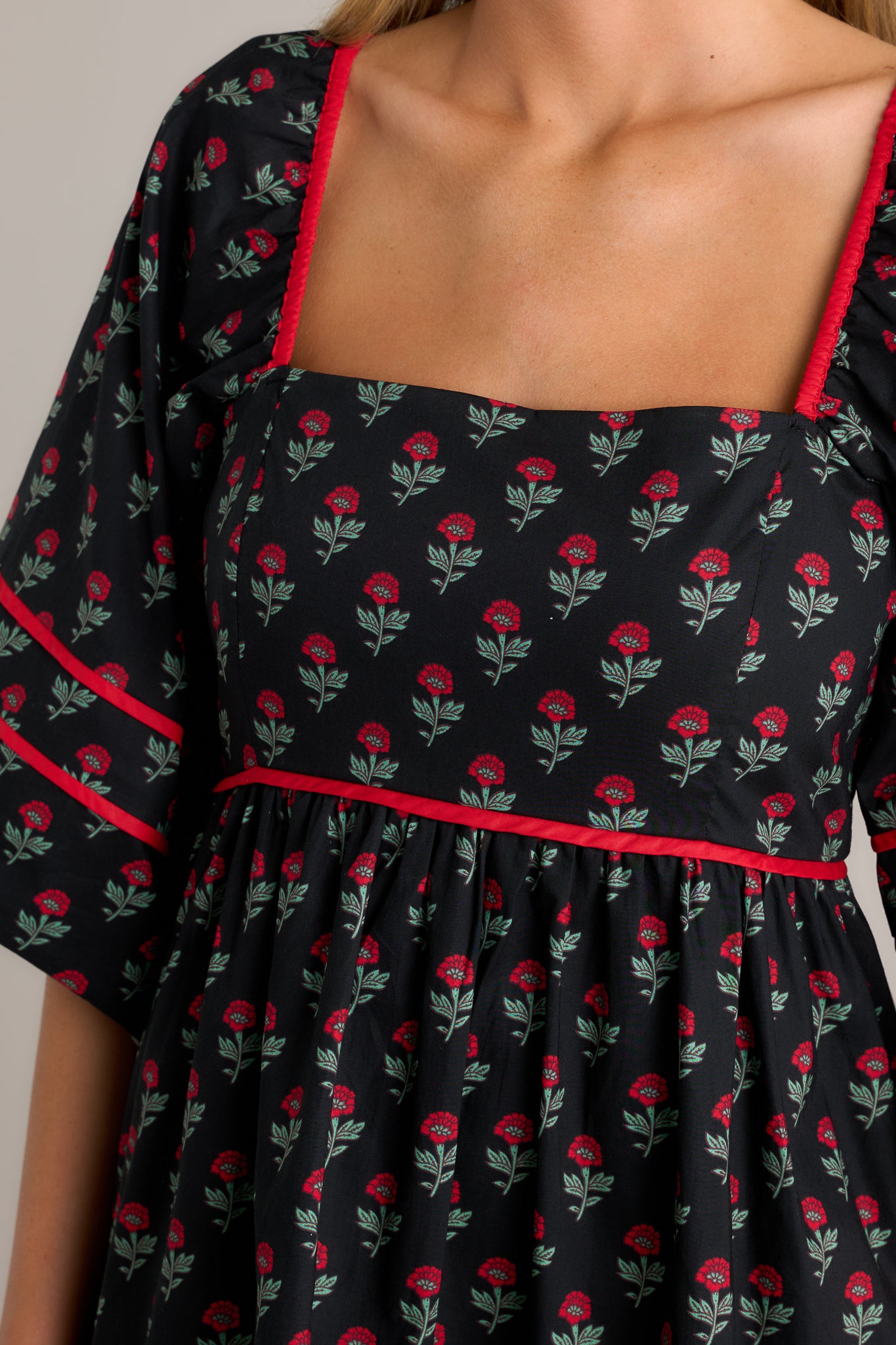 Close-up of the floral puff sleeve dress showing the square neckline, functional hip pockets, and elastic cuffed half sleeves.