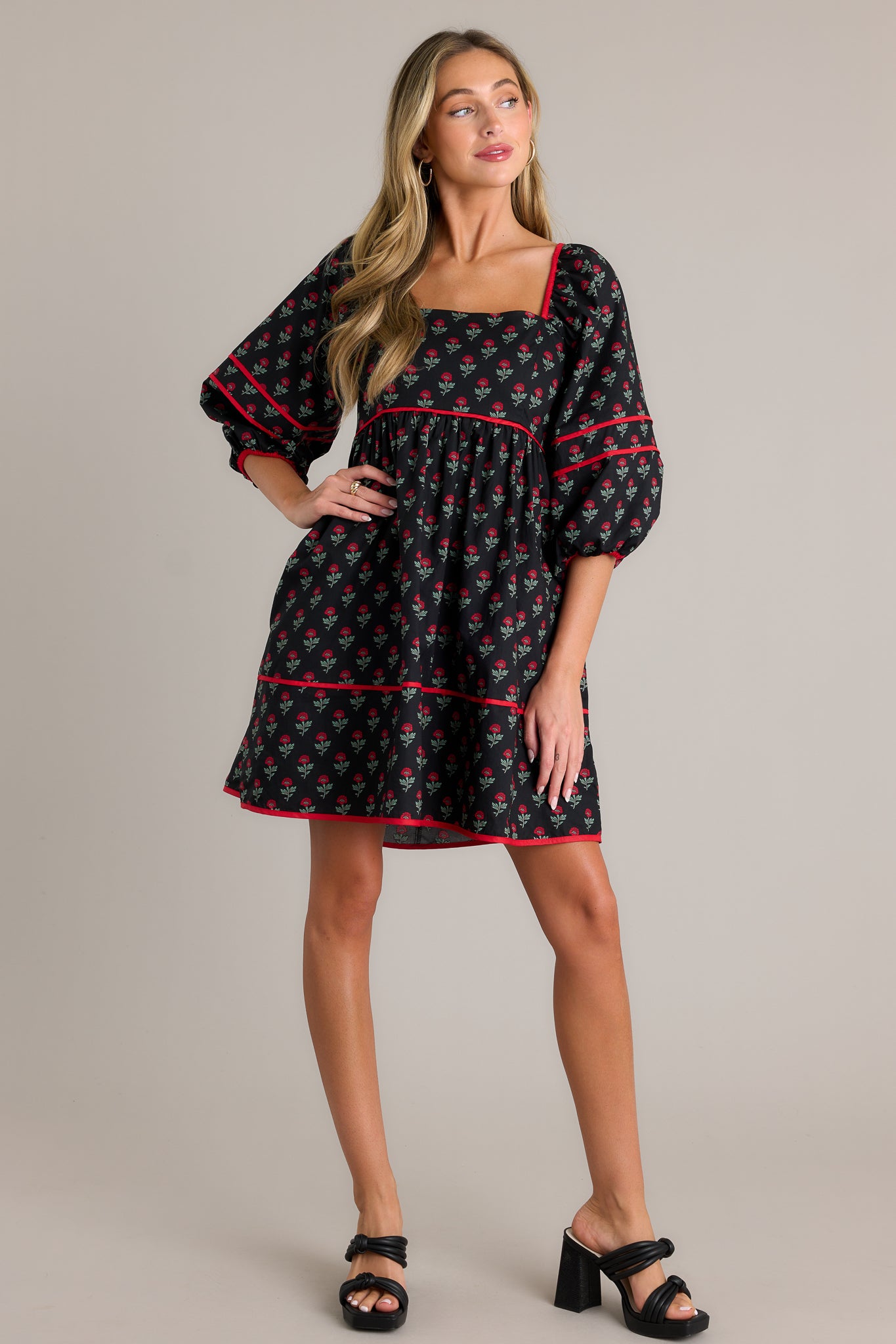 Front angled view of a floral puff sleeve dress featuring a square neckline, functional hip pockets, a tiered design, a self-tie back, a smocked back, and elastic cuffed half sleeves