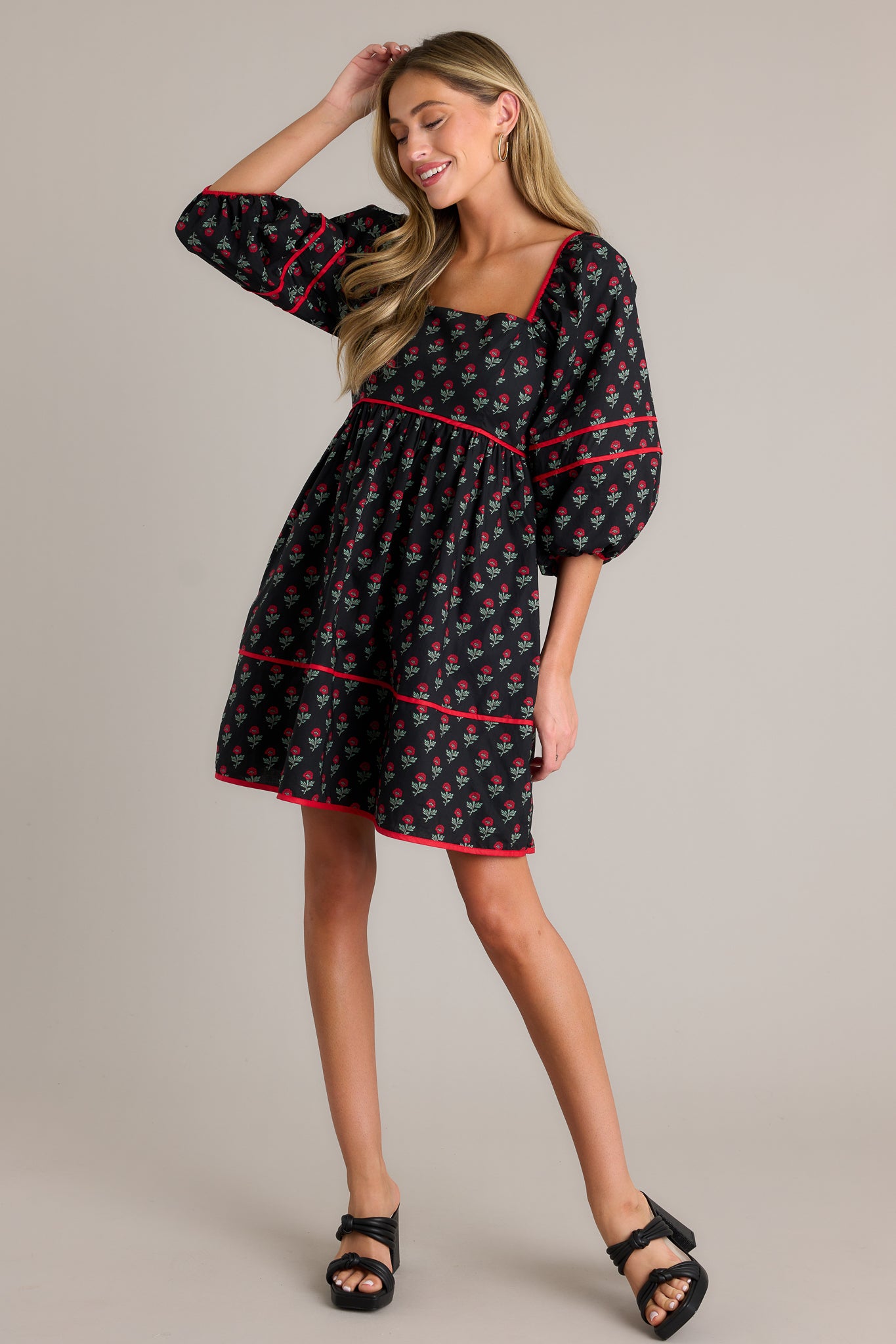 Action shot of a floral puff sleeve dress displaying the fit and movement, highlighting the square neckline, functional hip pockets, tiered design, self-tie back, smocked back, and elastic cuffed half sleeves