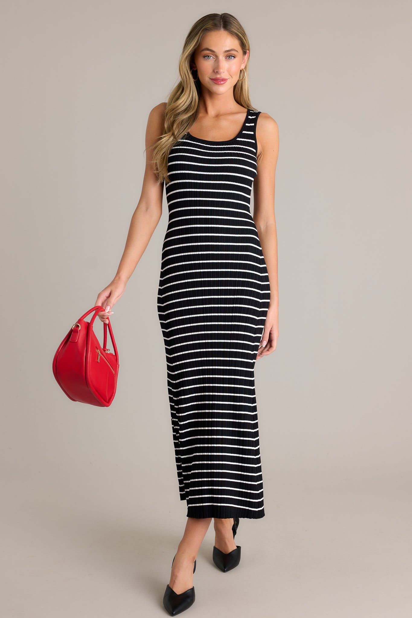 Action shot of a black stripe dress displaying the fit and movement, highlighting the scoop neckline, classic stripe design, soft ribbed texture, and bodycon fit.