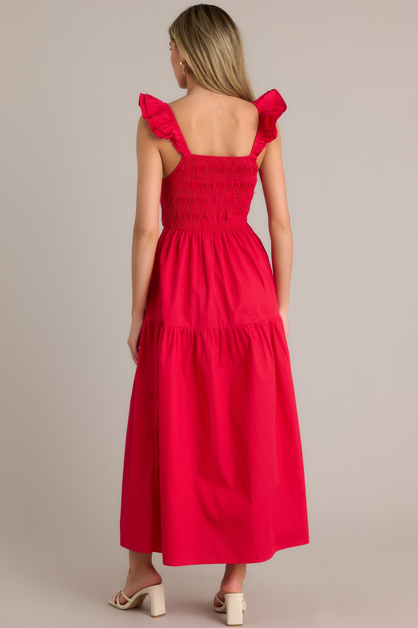 Back view of a red midi dress highlighting the fully smocked back, tiered design, and flowing silhouette.