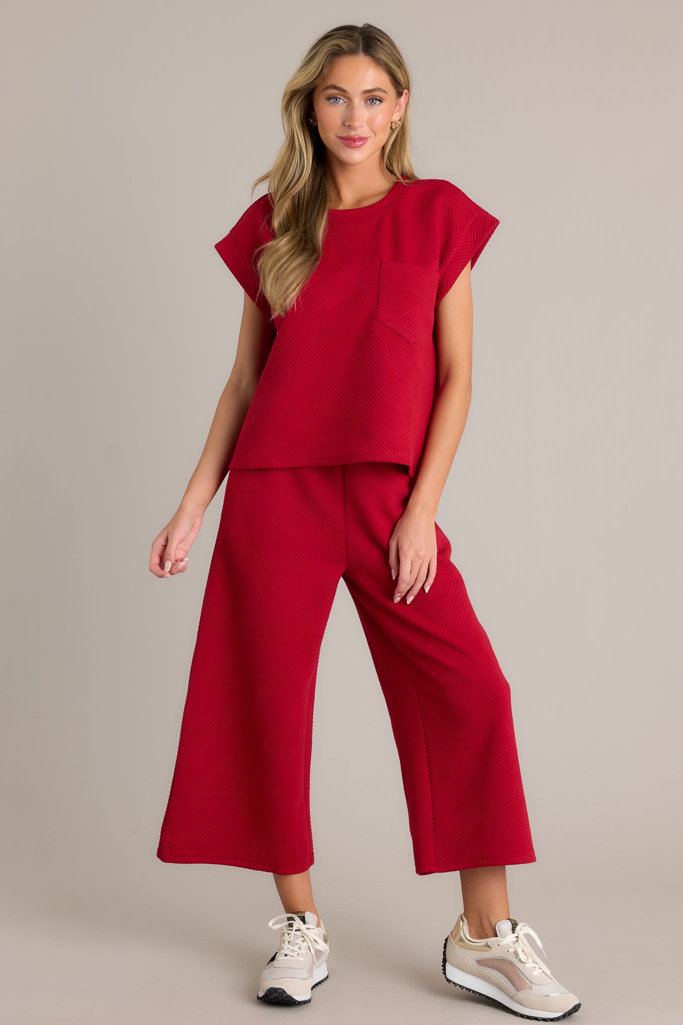 Front angled view of a scarlet red top featuring a crew neckline, a functional breast pocket, subtle crisscross texturing, and wide cuffed short sleeves