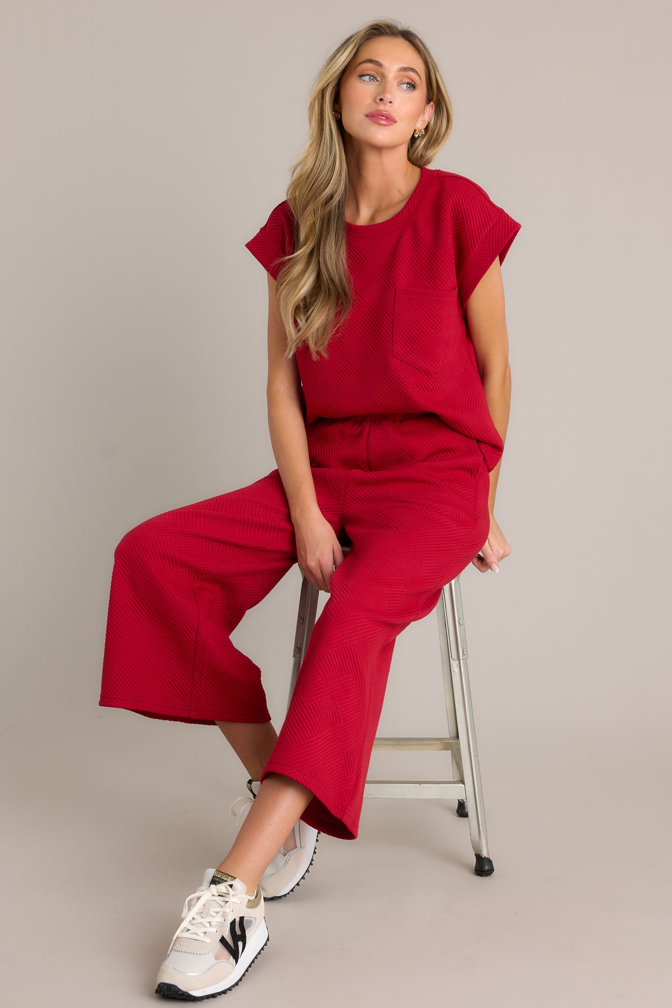 These red pants feature a high-waisted design, an elastic waistband, functional hip pockets, a textured crisscross pattern, and a wide-leg cut.